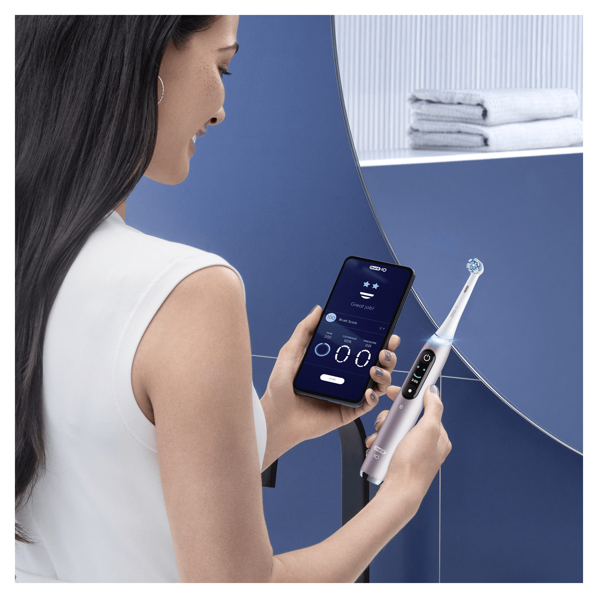 Kobieta używająca inteligentnej szczoteczki do zębów, pokazująca aplikację na telefonie i niebieską łazienkę.