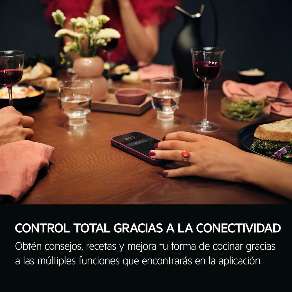 Nakrycie stołu z ludźmi, jedzeniem i smartfonem. Tekst mówi o kontroli poprzez łączność i aplikację.