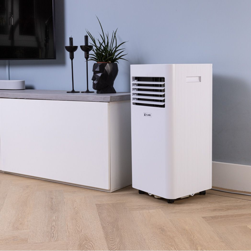 White portable air conditioner next to a white cabinet and blue wall in a room.