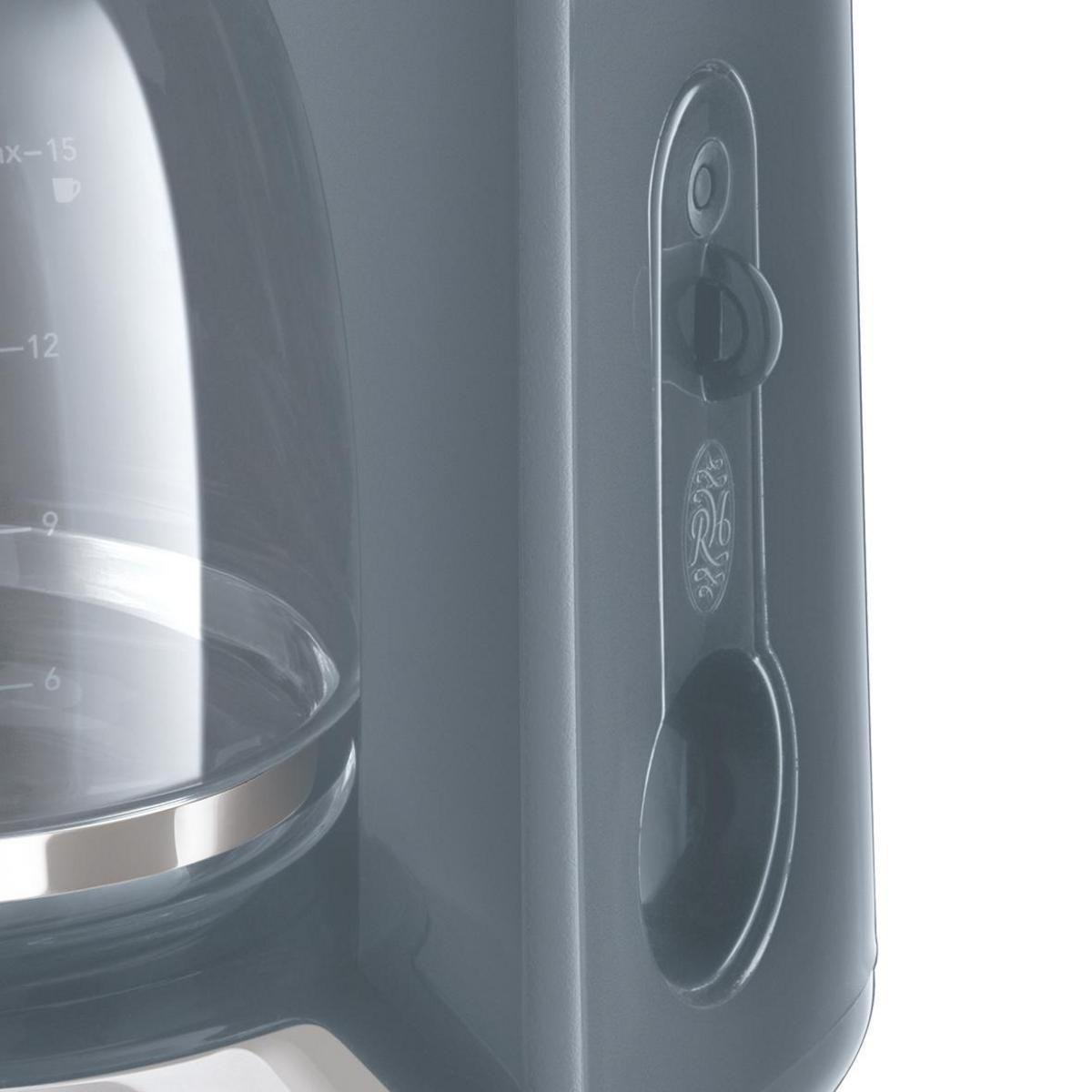 Nahaufnahme einer grauen Kaffeemaschine mit einer transparenten Glaskaraffe und einem Kaffeelöffel.
