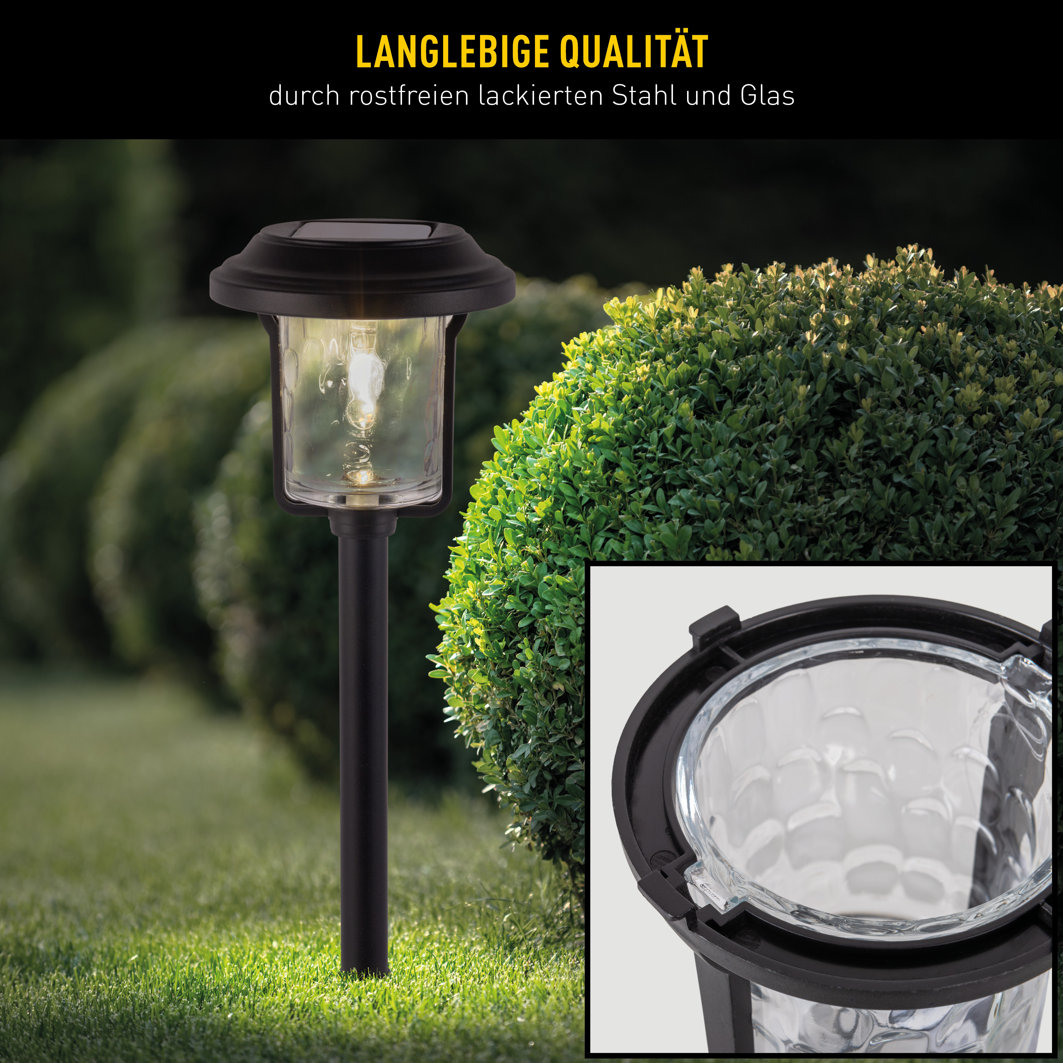 Eine schwarze Solar-Gartenleuchte in einem Garten. Sie hat eine Glaslampe und ein kleines Bild.
