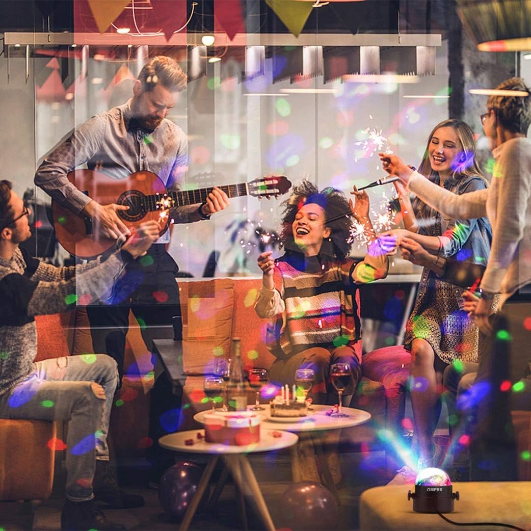 Eine Gruppe von Leuten genießt eine Party. Ein Mann spielt Gitarre, andere halten Wunderkerzen, und ein Lichtprojektor ist an.