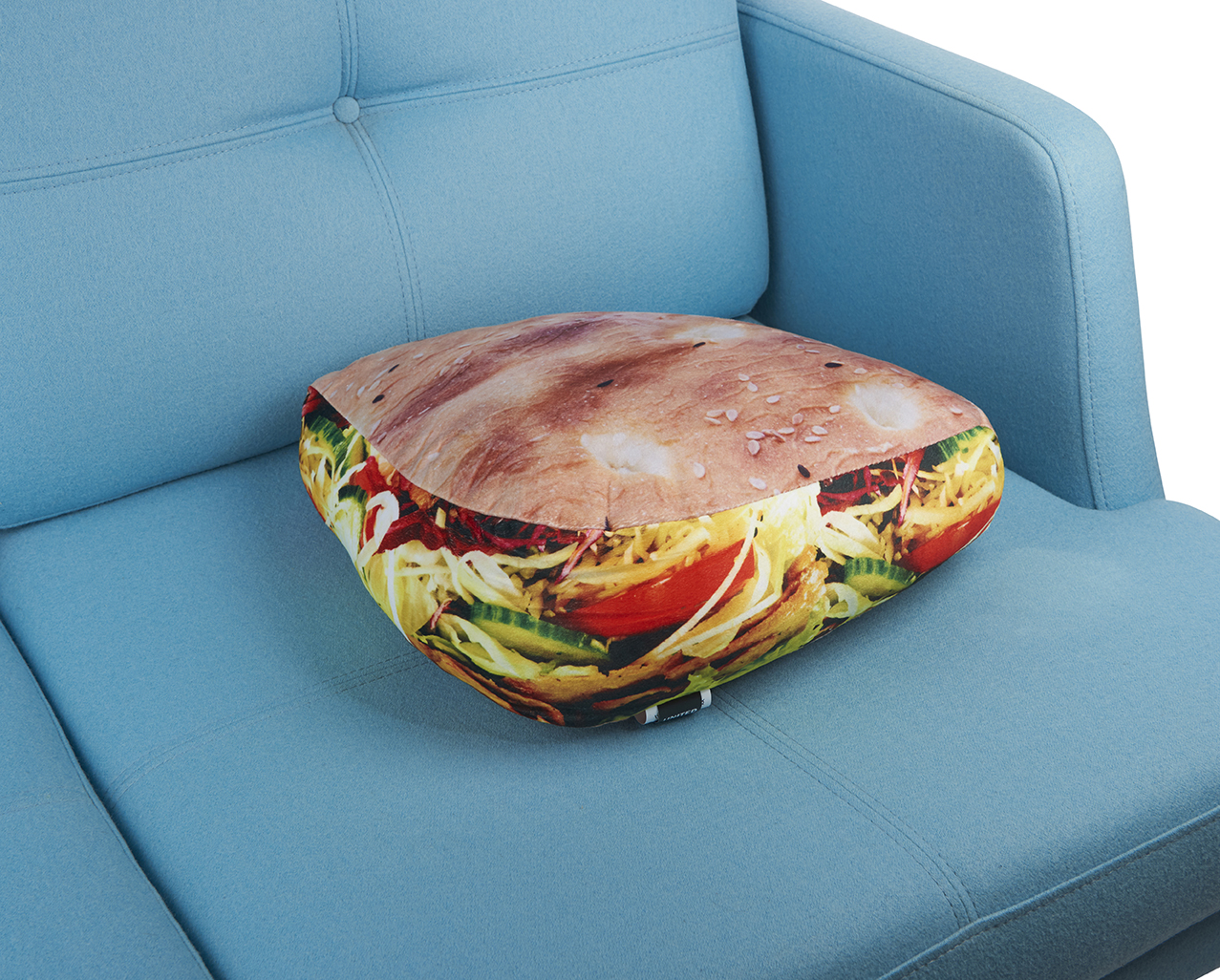 Ein kissenförmiges Sandwich liegt auf einem blauen Sofa.
