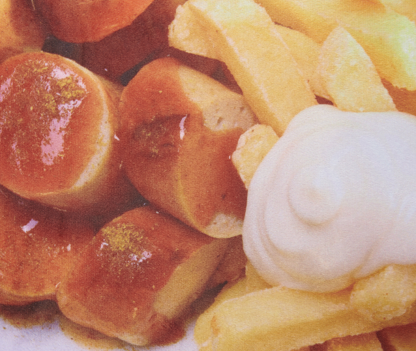 Nahaufnahme eines Tellers mit Currywurst, Pommes Frites und Mayonnaise. Die Wurst ist geschnitten und mit Currypulver bedeckt.