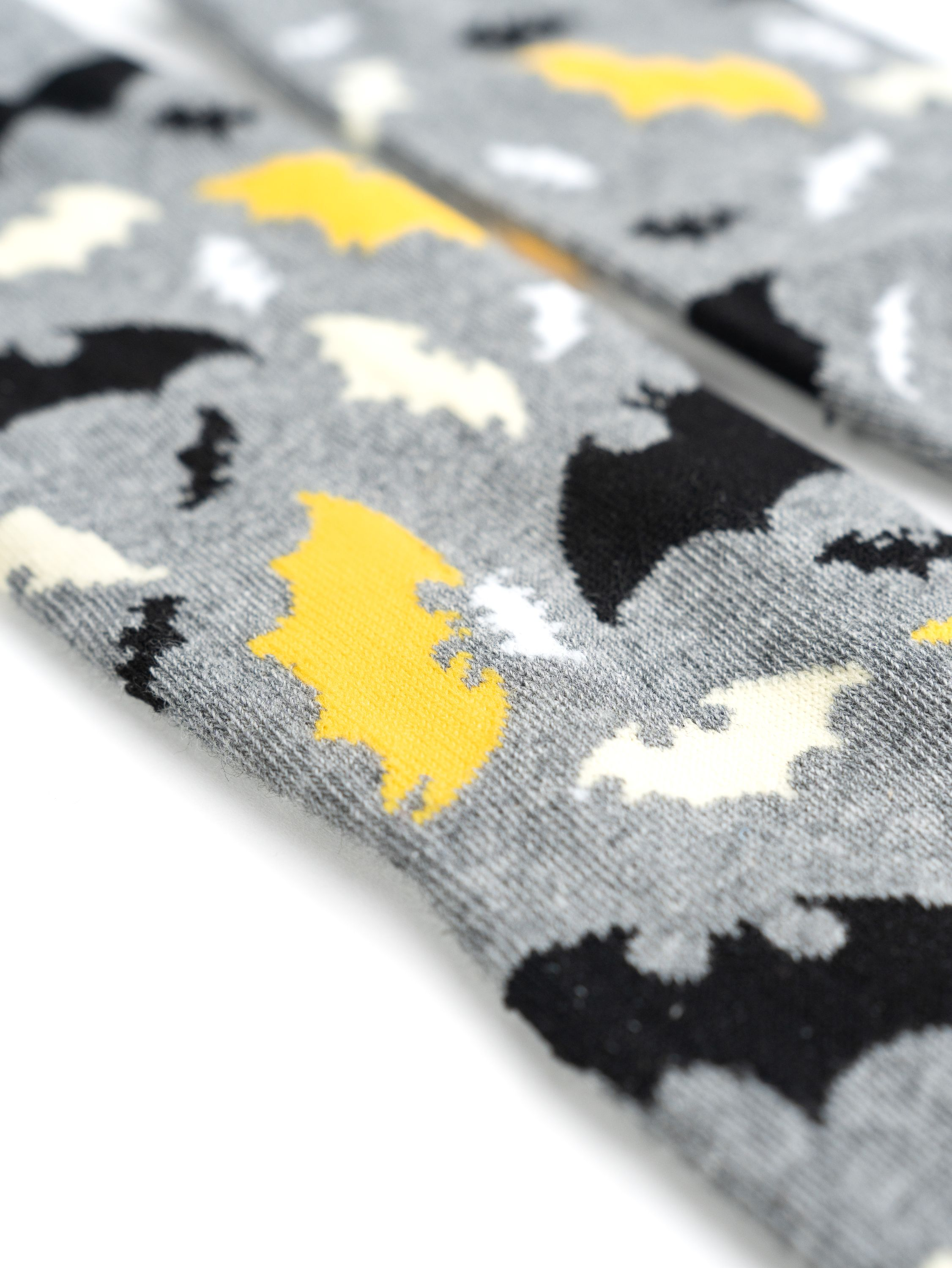 Nahaufnahme grauer Socken mit gelben und schwarzen Fledermausmustern.