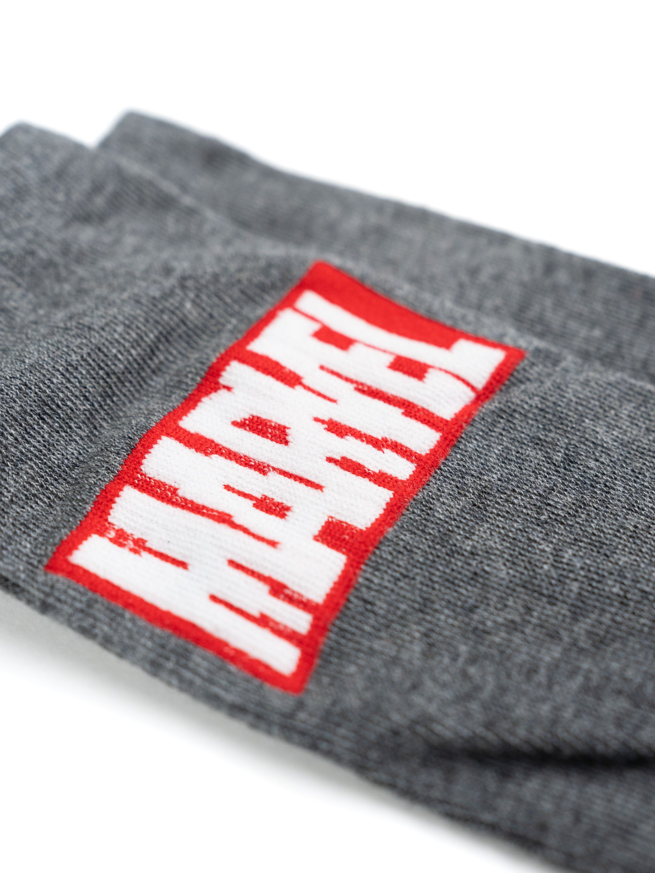 Graue Socken mit dem Marvel-Logo in Weiß und Rot, gefaltet auf weißem Hintergrund.