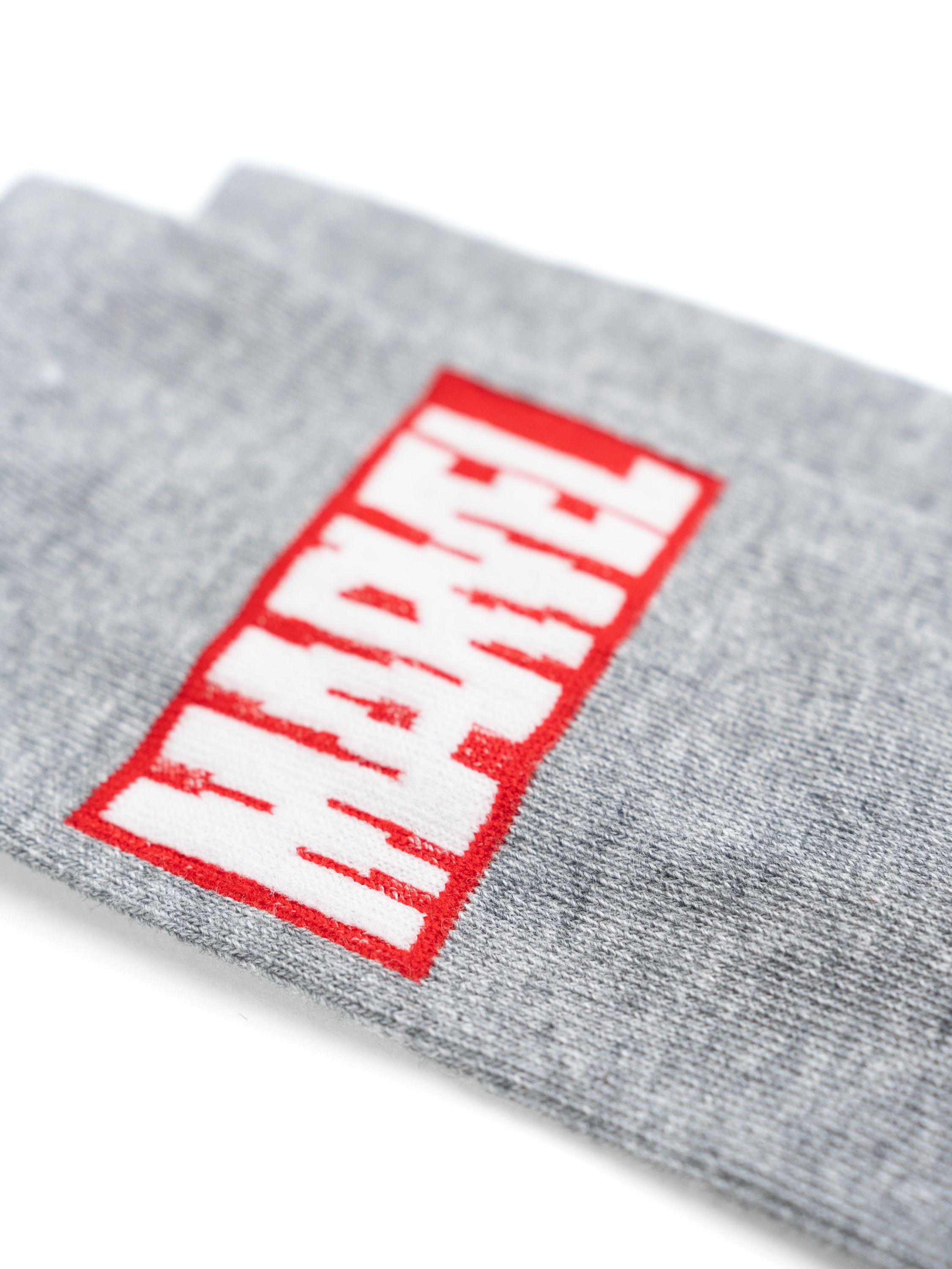 Nahaufnahme von grauen Socken mit dem roten 'MARVEL'-Logo darauf.