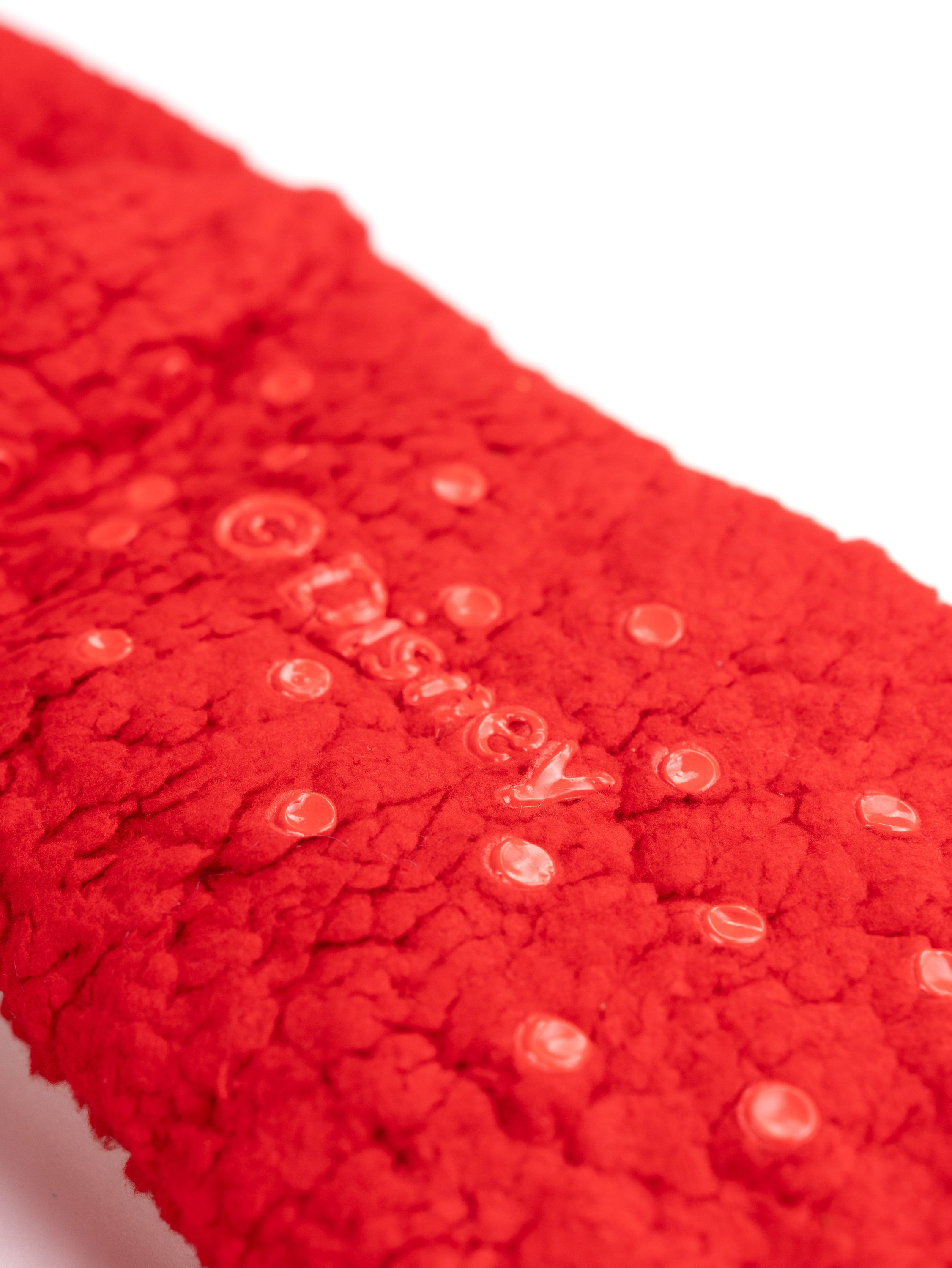 Roter Schwamm mit Wassertropfen. Die Tropfen sind klar und der Schwamm ist strukturiert.