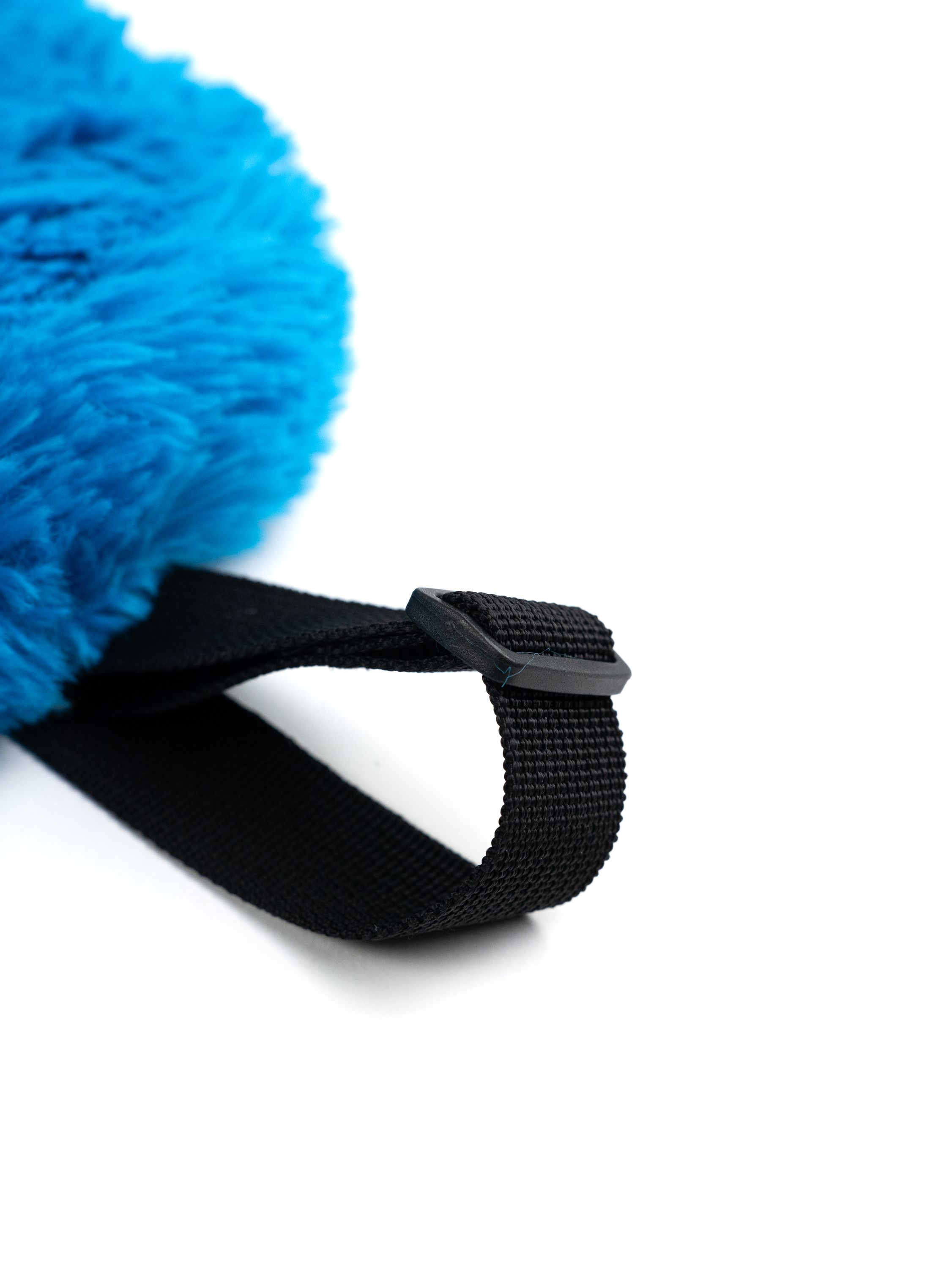 Nahaufnahme eines schwarzen Riemens mit einem blauen, flauschigen Objekt und einer Schnalle auf weißem Hintergrund.
