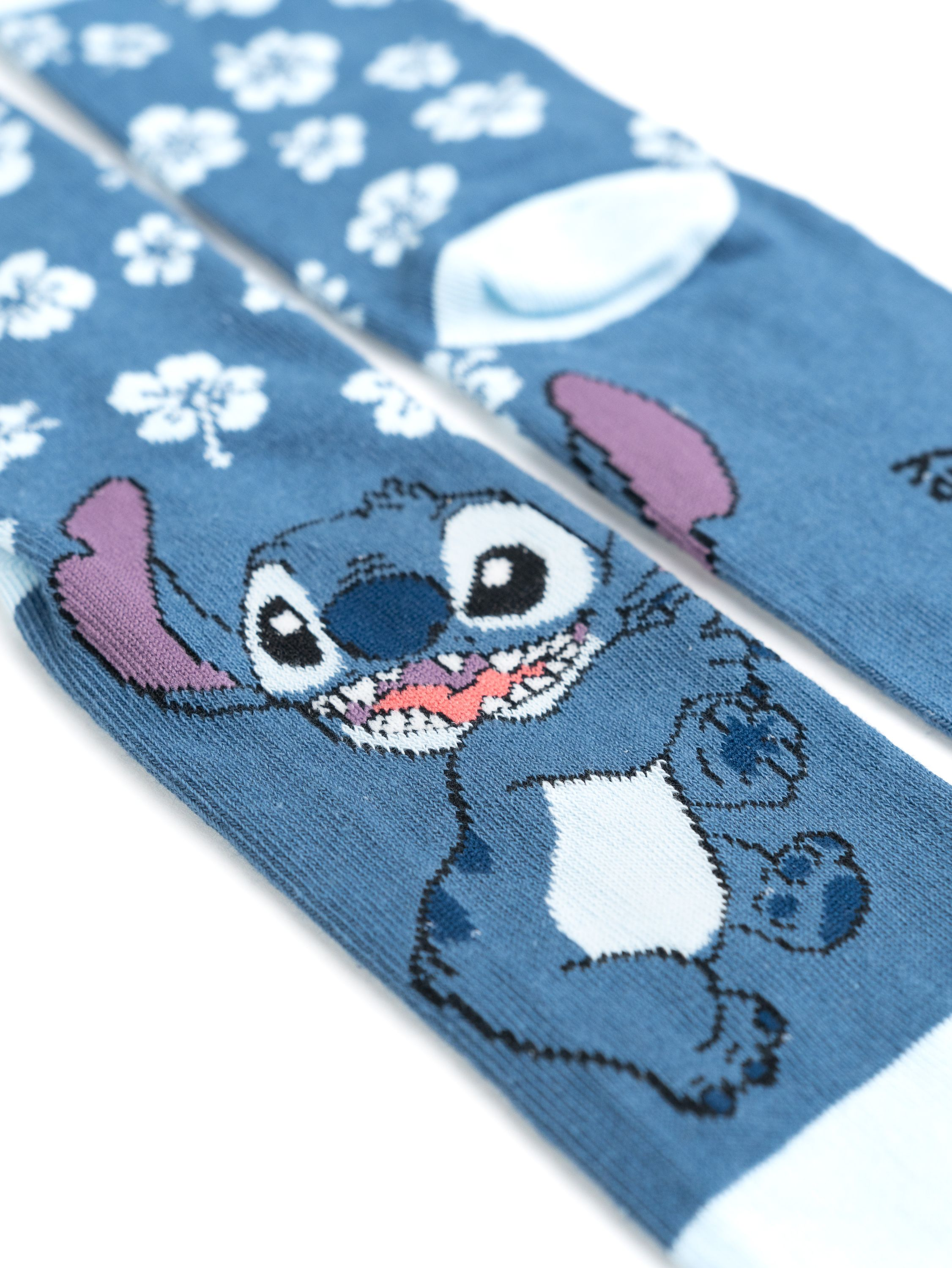 Paar Stitch-Socken. Eine Socke zeigt Stitch, die andere weiße Blumen auf Blau.