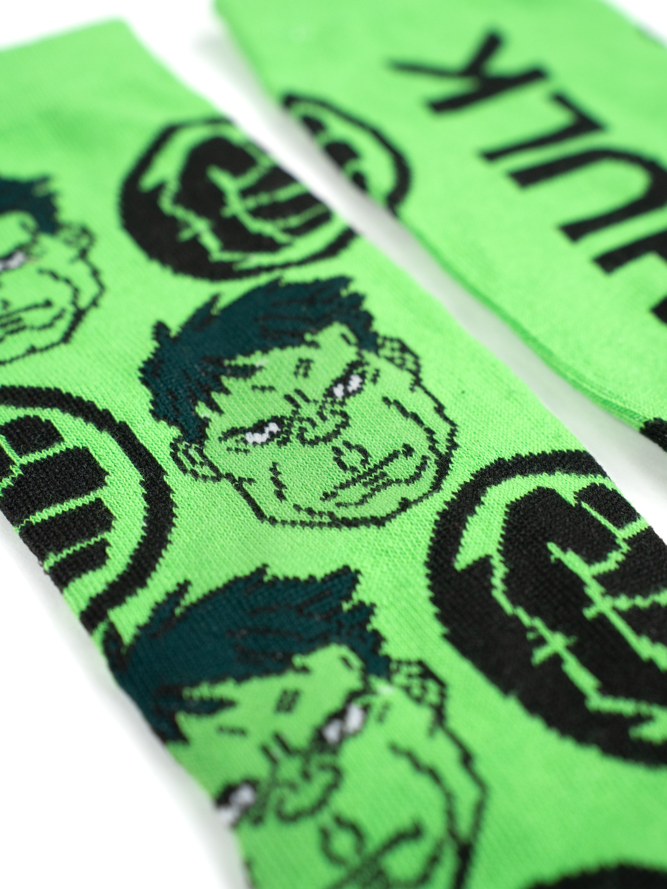 Grüne Socken mit Hulk-Gesichtern und Logo auf weißem Hintergrund.