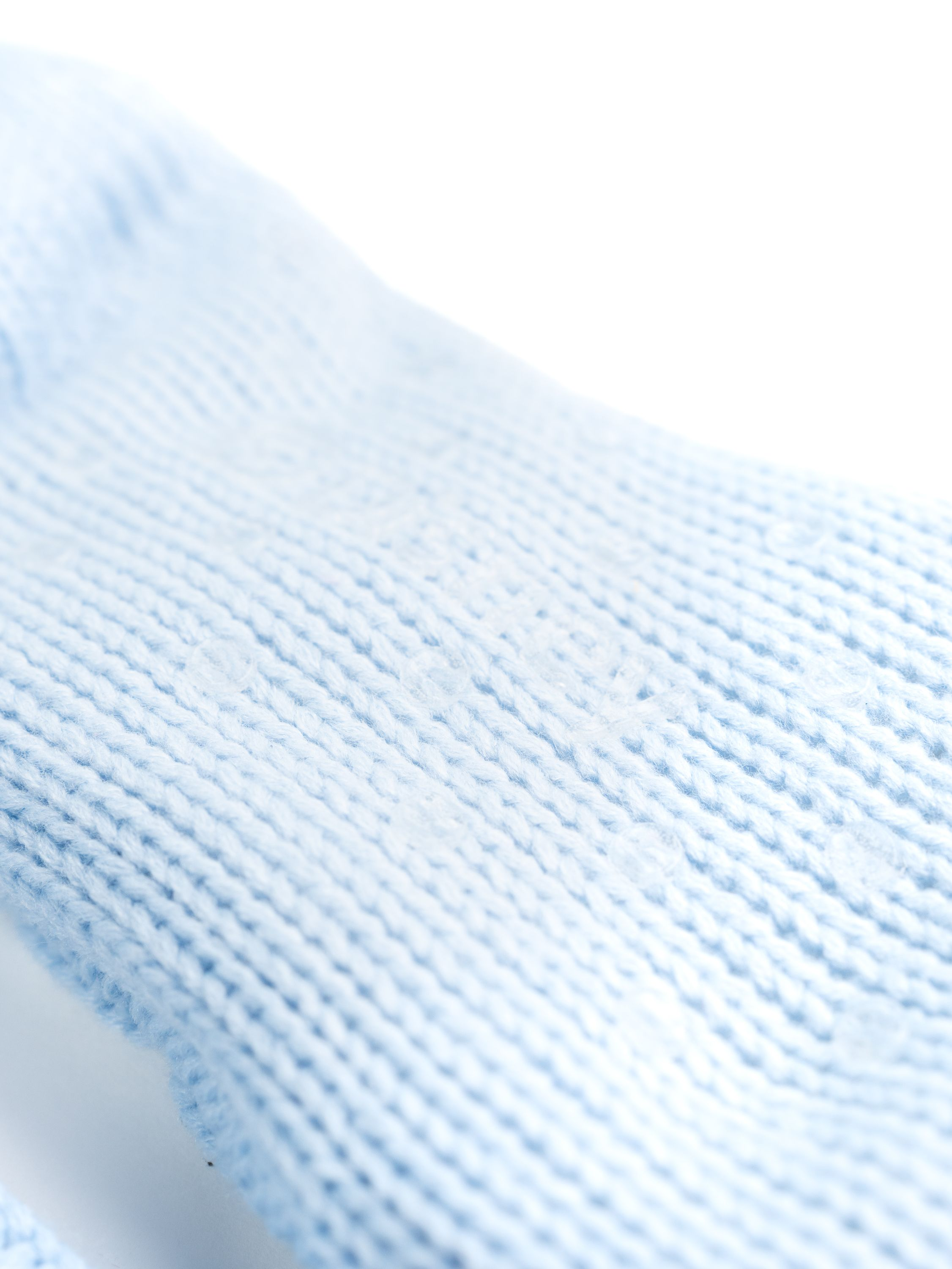 Nahaufnahme von hellblauem Strickstoff mit weißem Hintergrund.