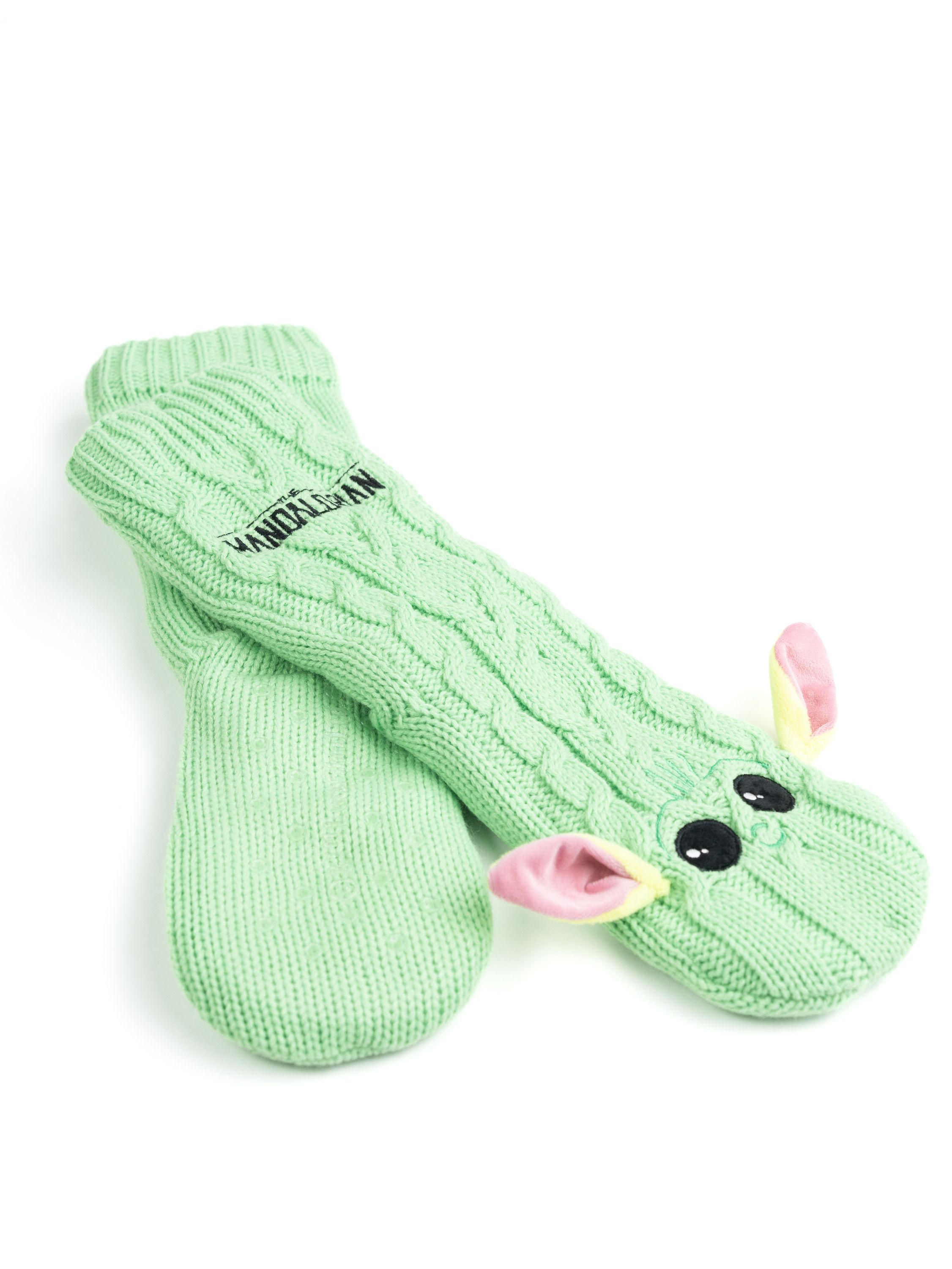 Grüne gestrickte Baby-Yoda-Fäustlinge mit rosa Ohren und schwarzen Augen auf weißem Hintergrund.