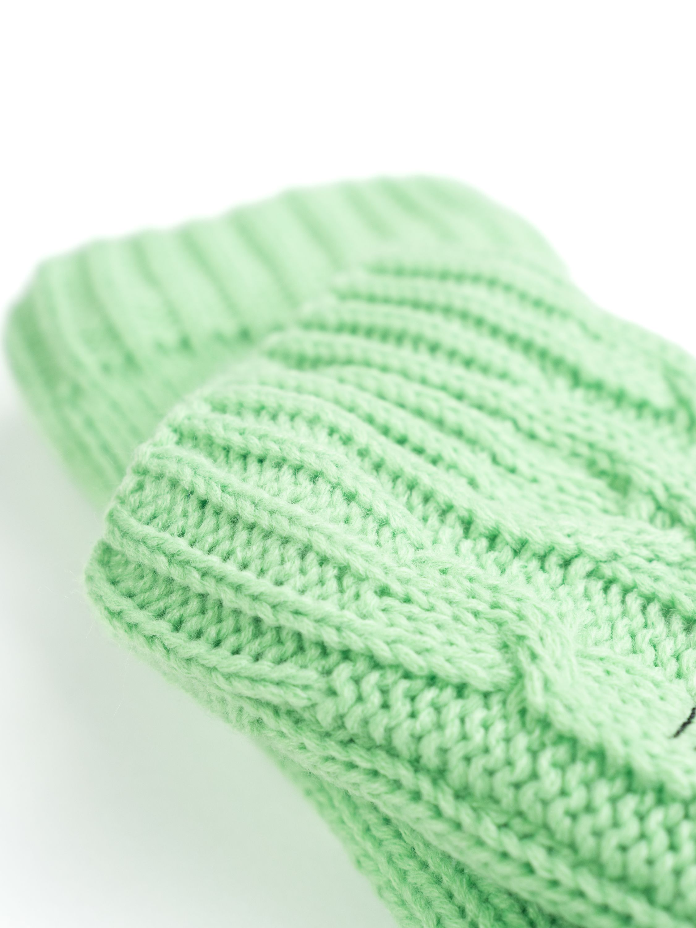 Grünes Strickstoffdetail, Nahaufnahme, das die Textur und das Muster zeigt.