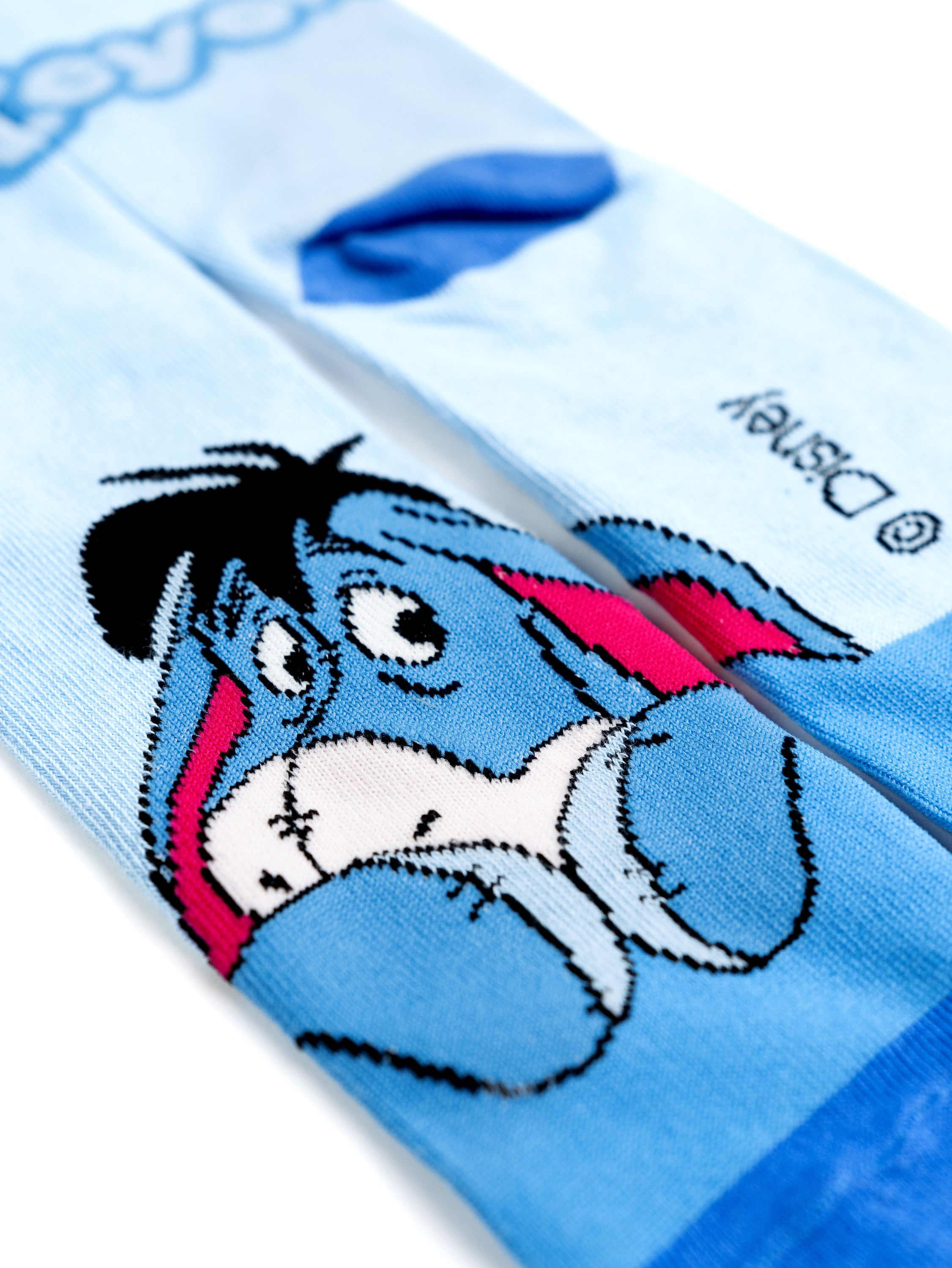 Ein Paar hellblaue Socken mit einem Nahaufbild der Eeyore-Figur.