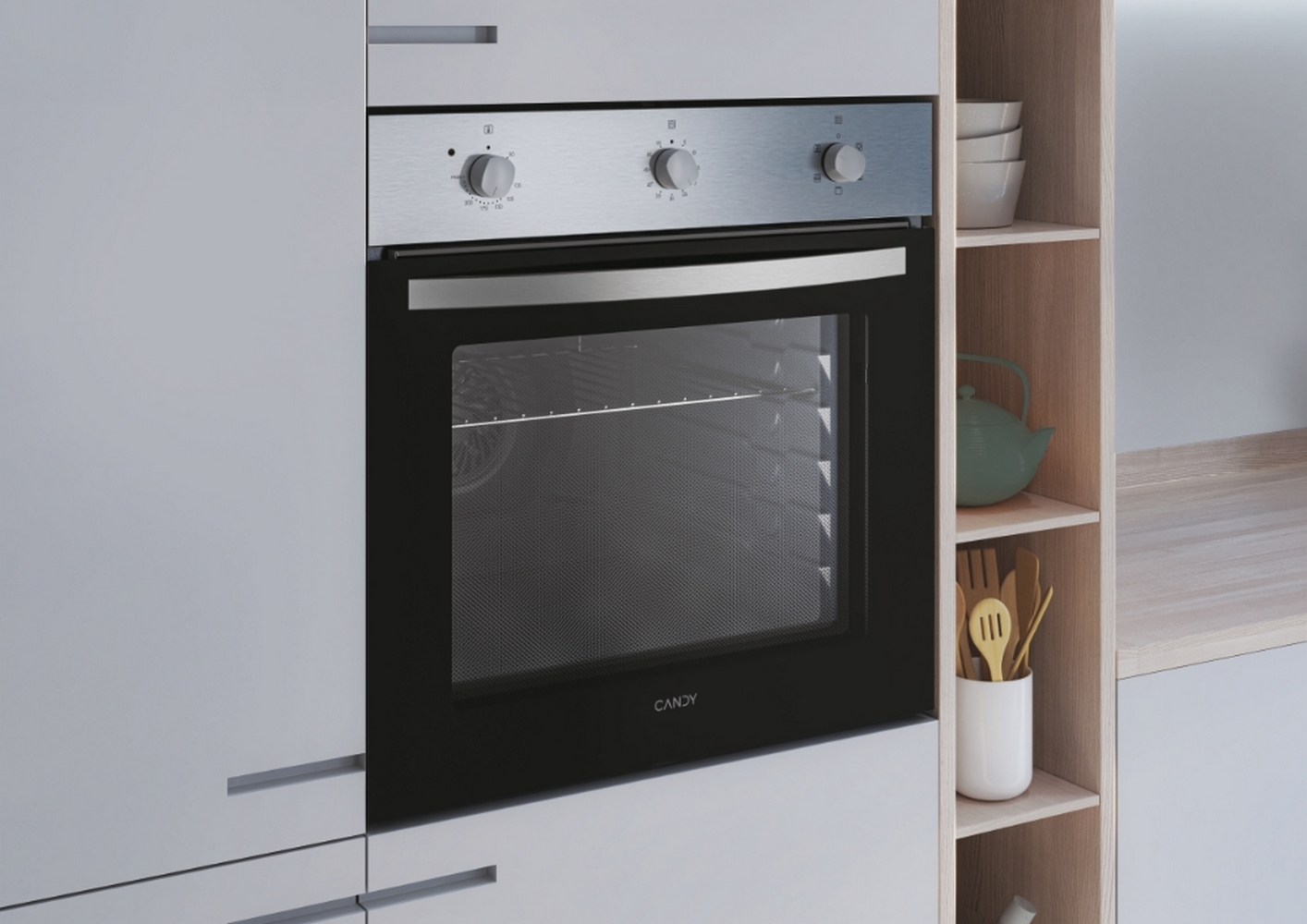 Forno CANDY incassato con comandi in alto, in un mobile da cucina, con una teiera verde.