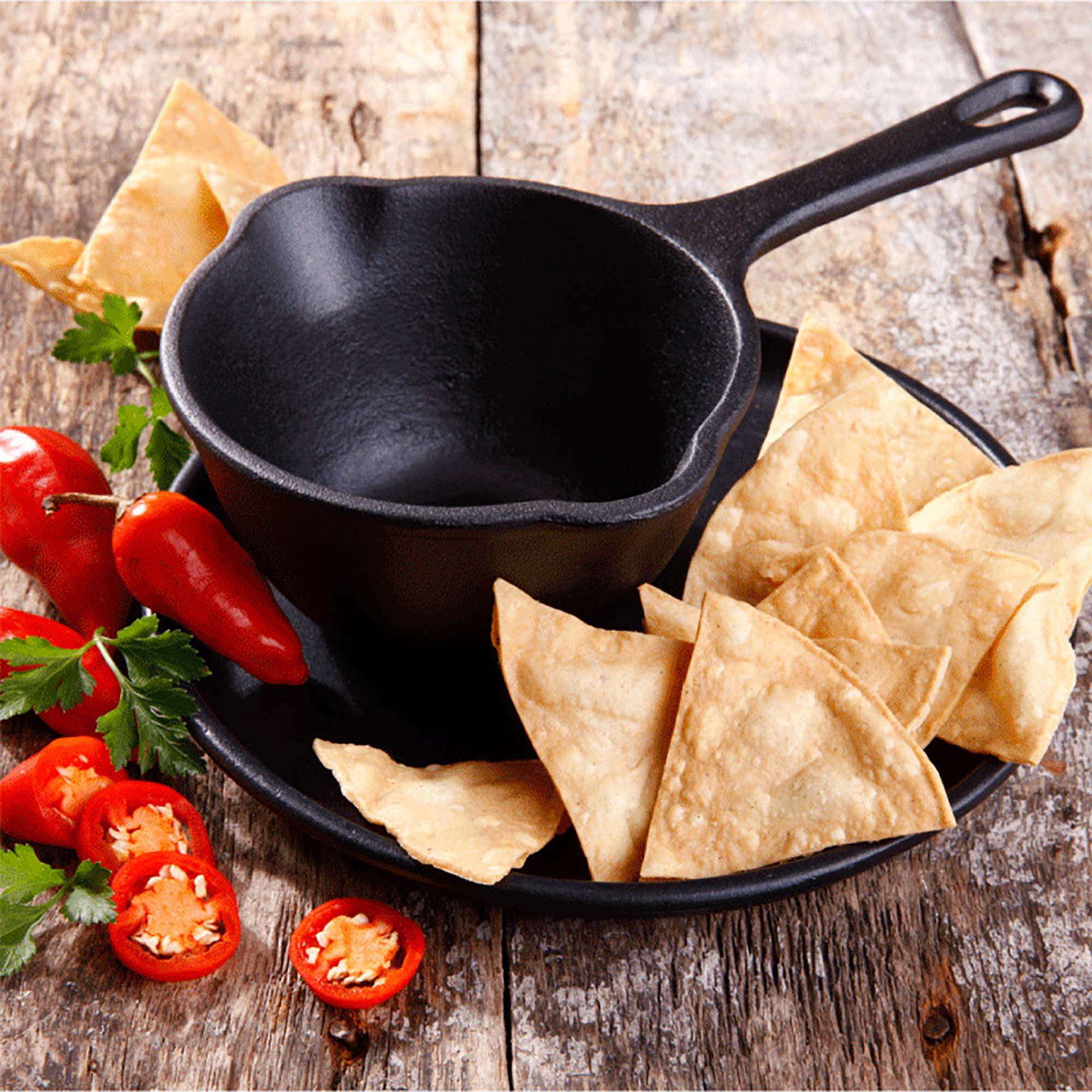 Una sartén de hierro fundido negra con un mango, y totopos, con chiles y tomates.
