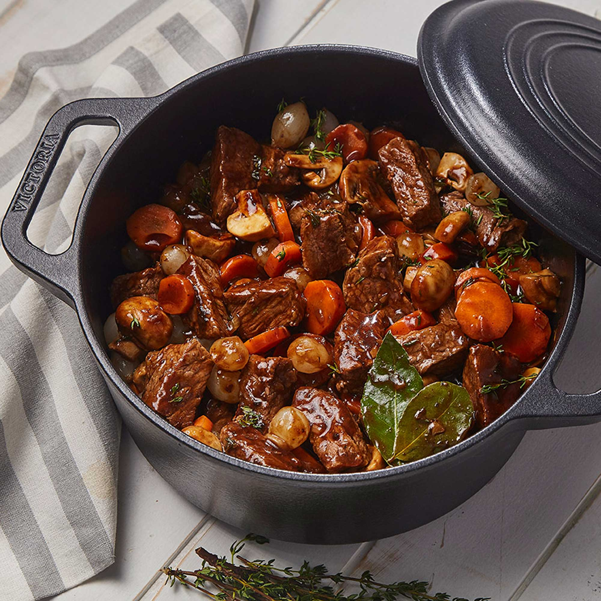 Una olla negra con estofado. Contiene zanahorias, carne, cebolla y champiñones.