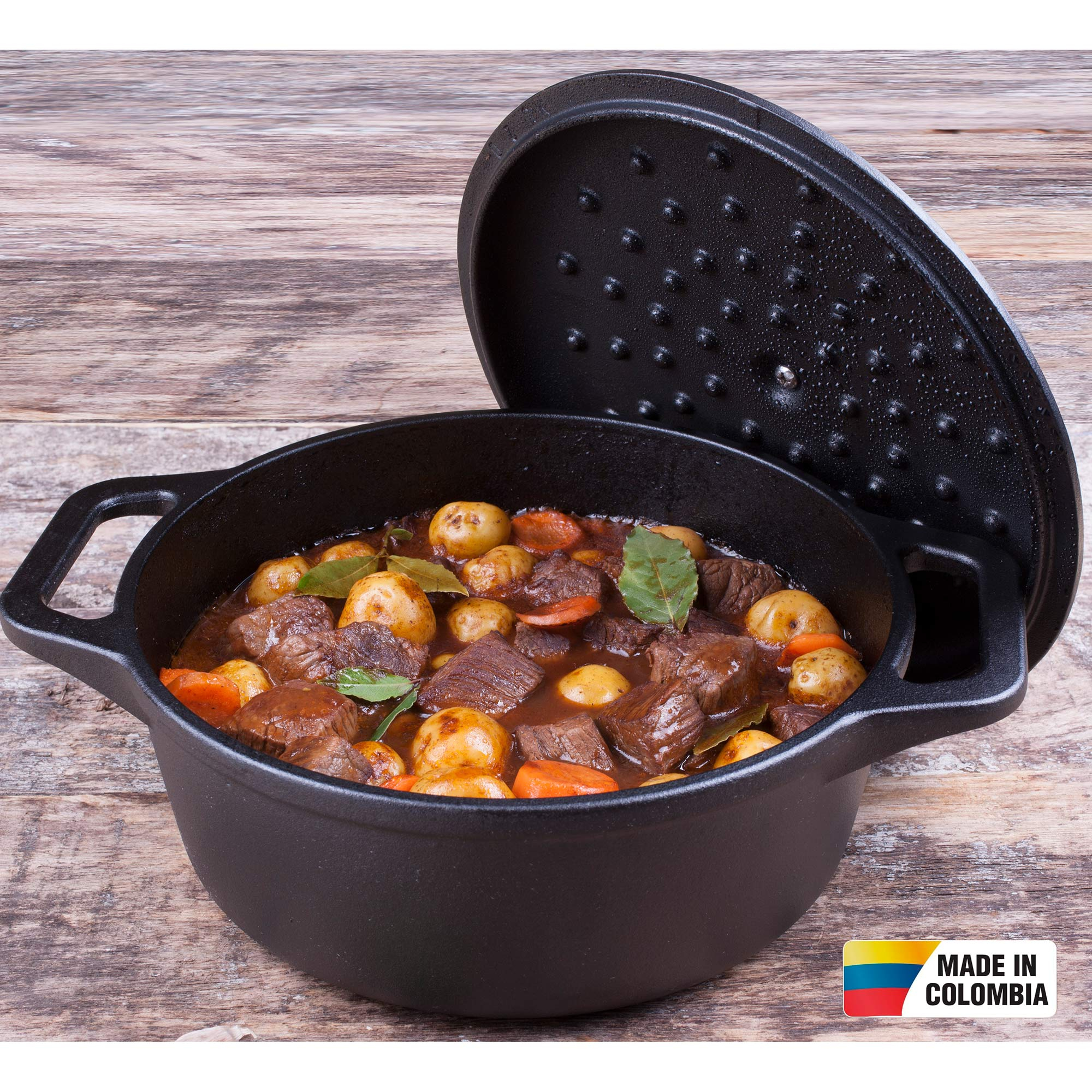 Olla negra con estofado y tapa. Mesa de madera, pegatina Hecho en Colombia.