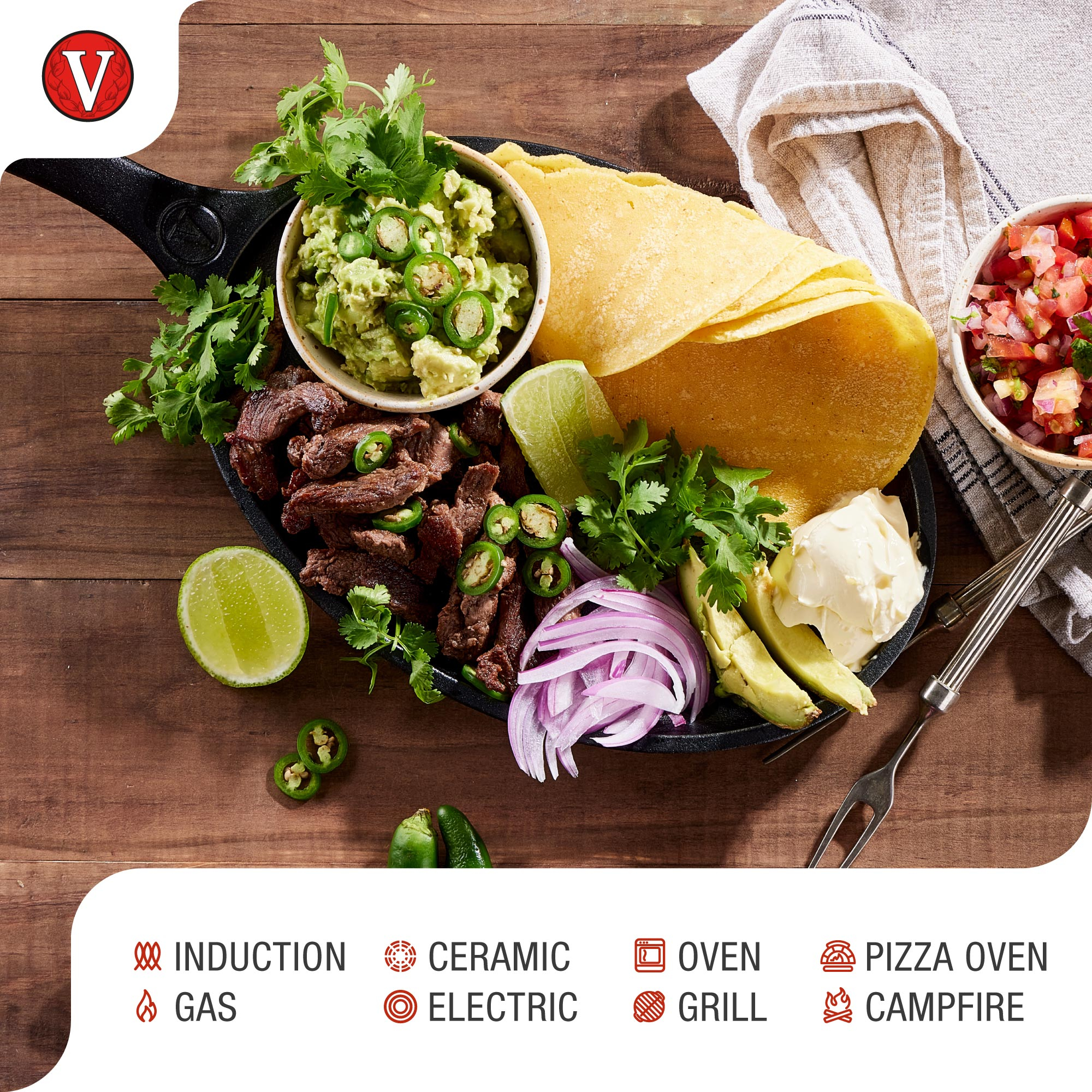 Eine gusseiserne Pfanne mit Guacamole, Fleisch, Tortillas und anderem mexikanischem Essen.