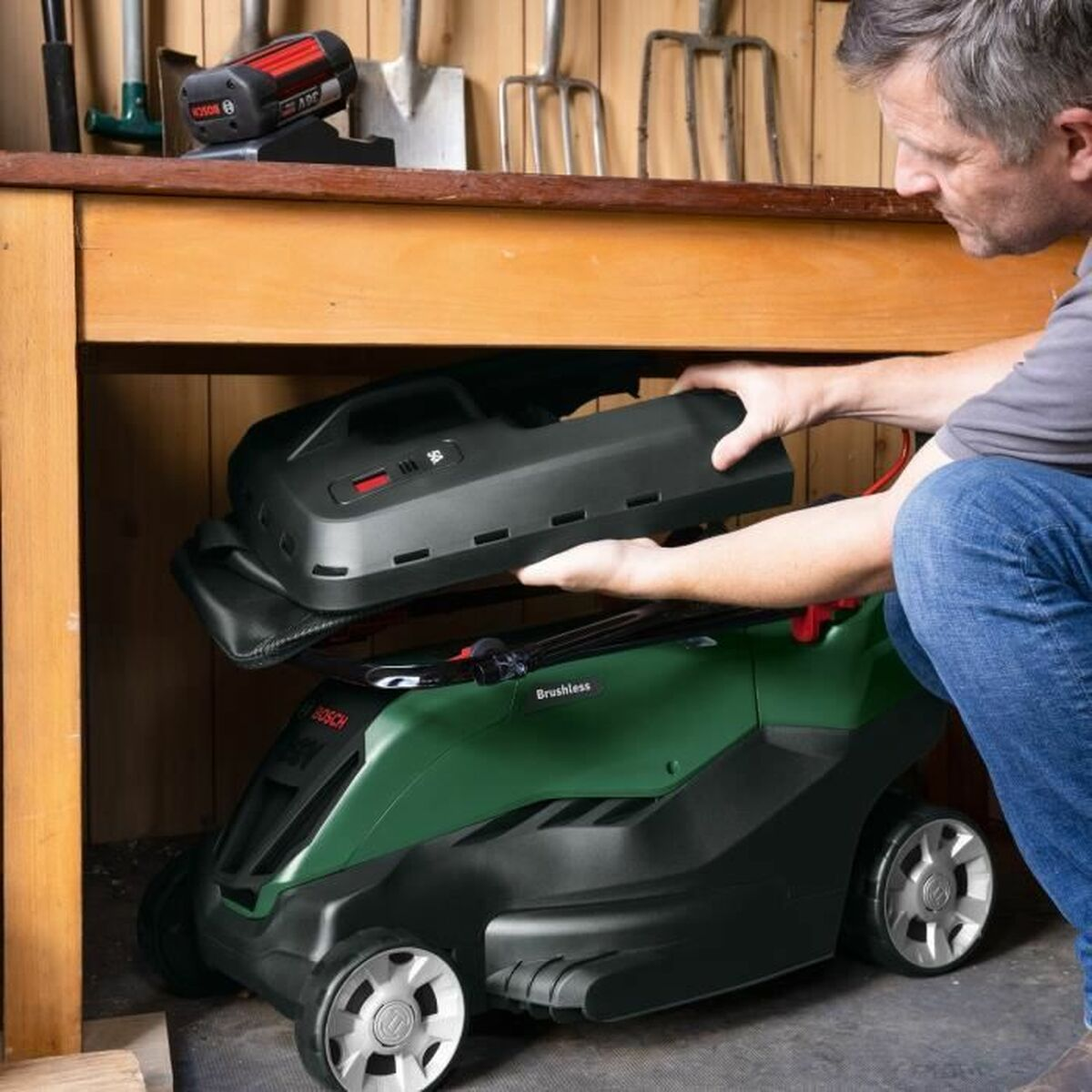 Persona colocando una batería en un cortacésped verde.
