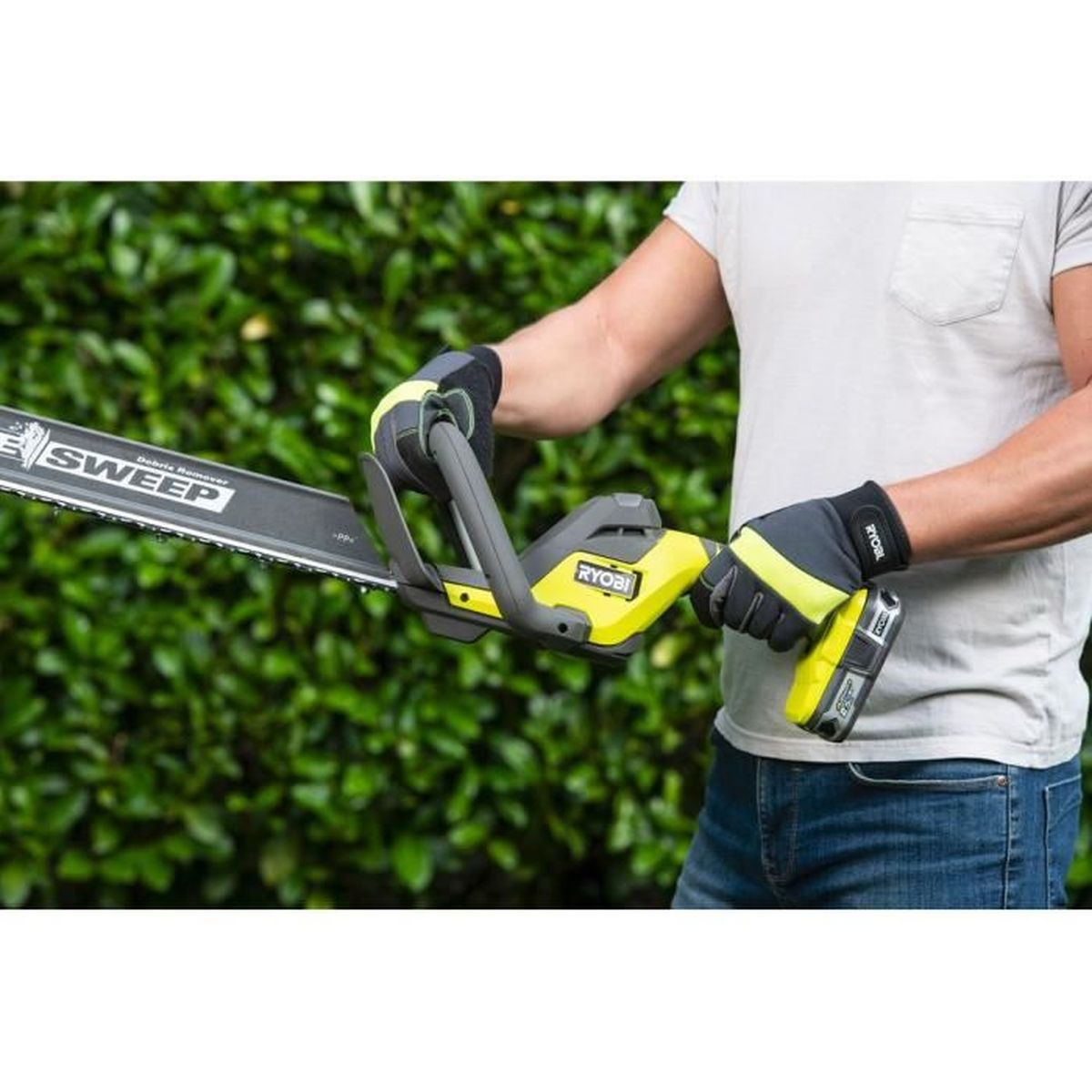 Person benutzt Heckenschere, trägt Handschuhe, in Gartenumgebung.