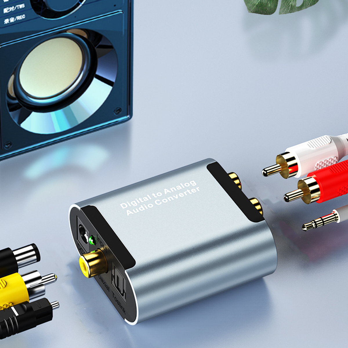 Ein Digital-Analog-Audio-Konverter mit verschiedenen angeschlossenen Kabeln und einem Lautsprecher in der Nähe.