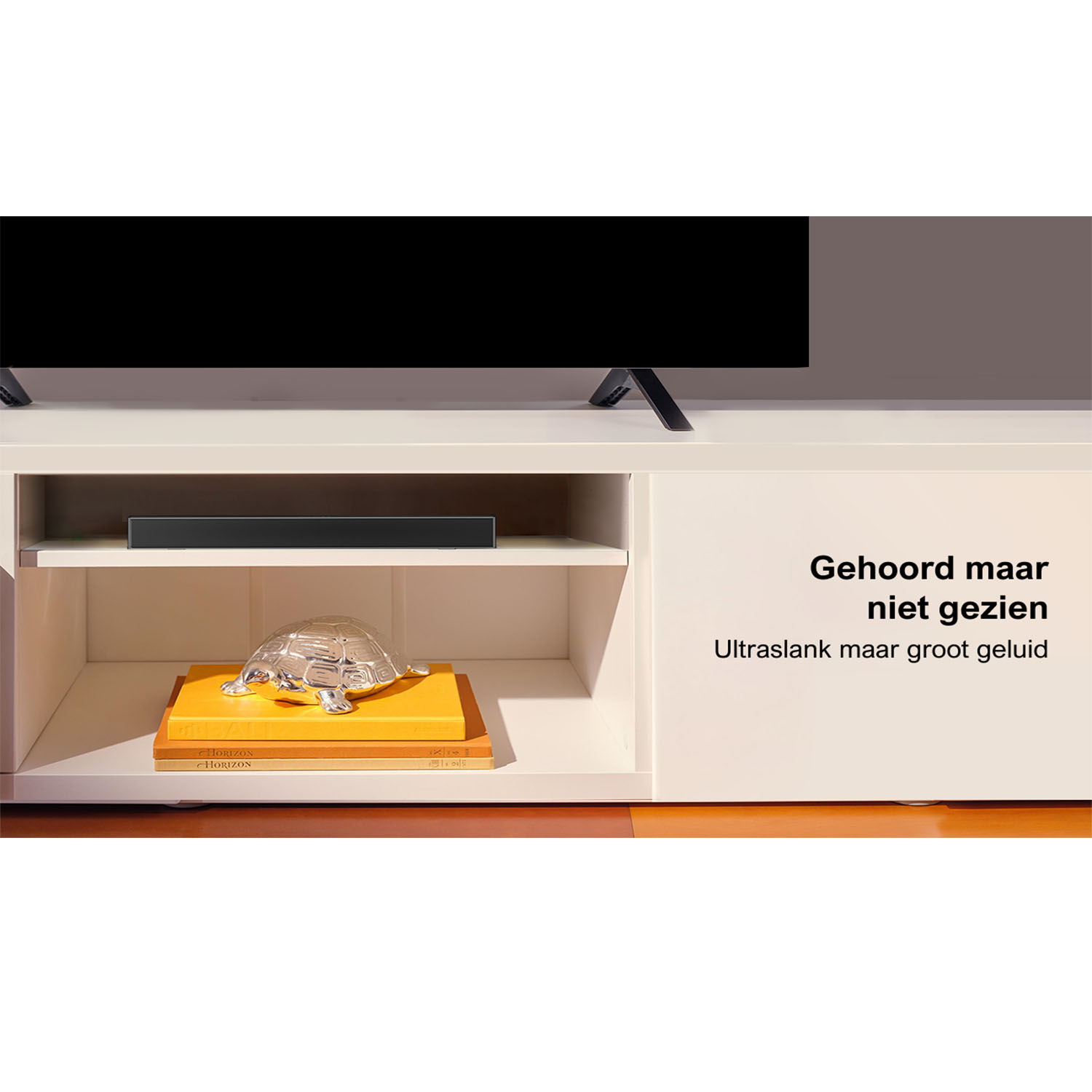 Een witte kast met een tv erbovenop. Op de kast een soundbar en boeken met een glazen schildpad.