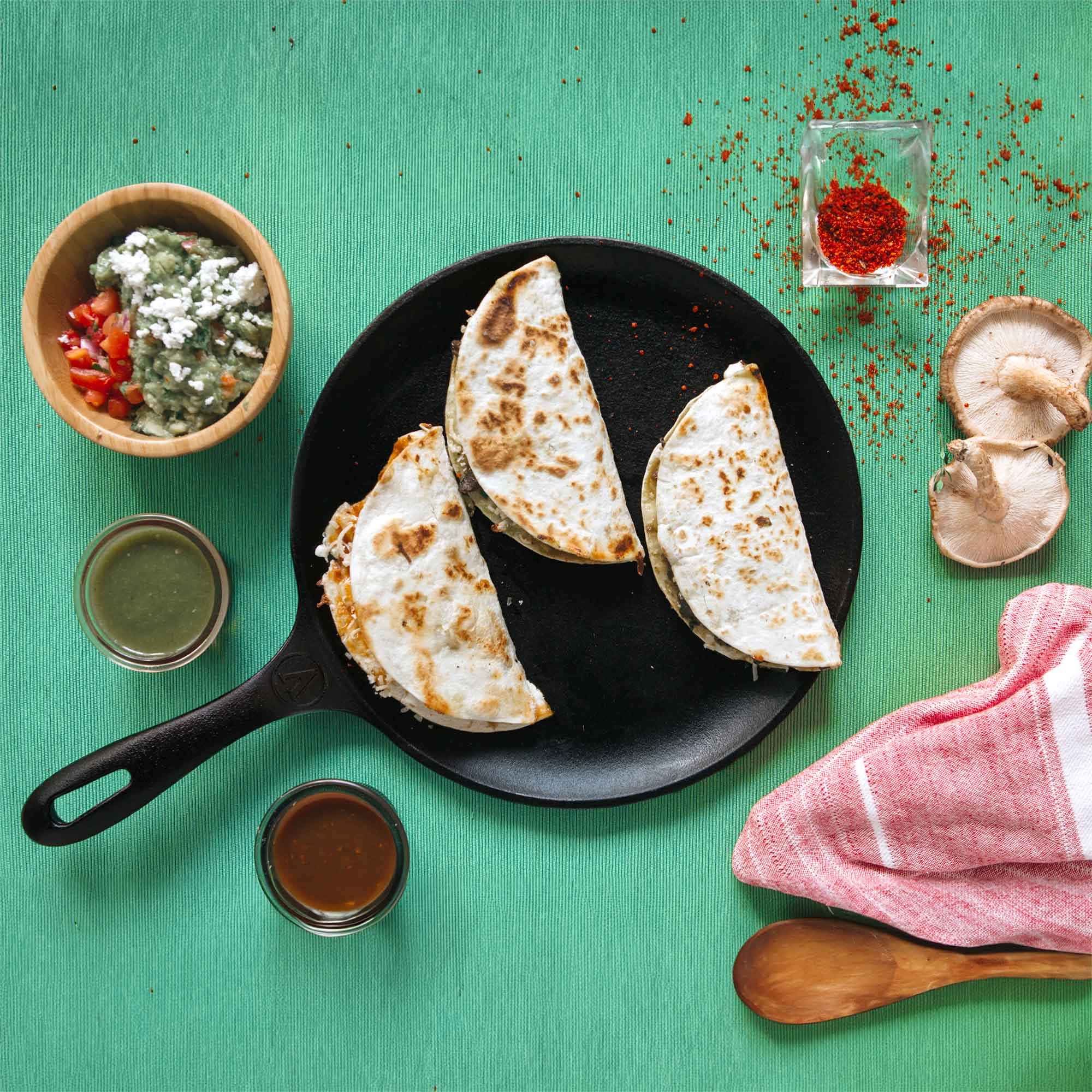 Quesadillas auf einer Pfanne mit Guacamole, Salsa und Pilzen.