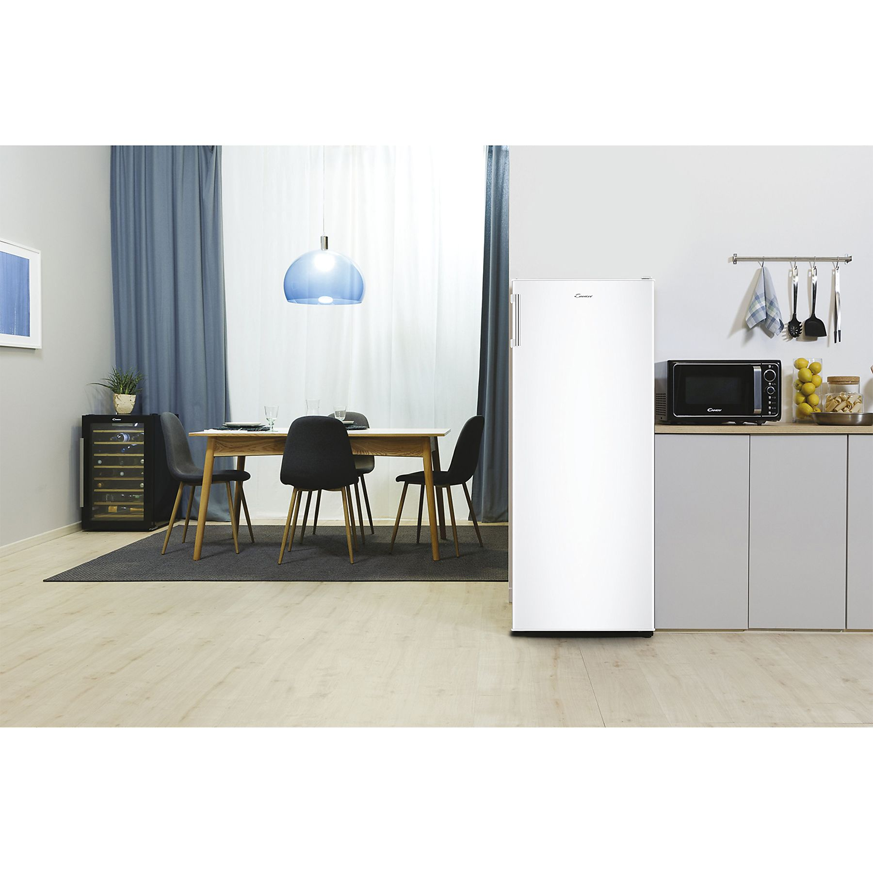 Cucina con frigorifero Candy bianco. Visibili anche tavolo, sedie e forno a microonde.