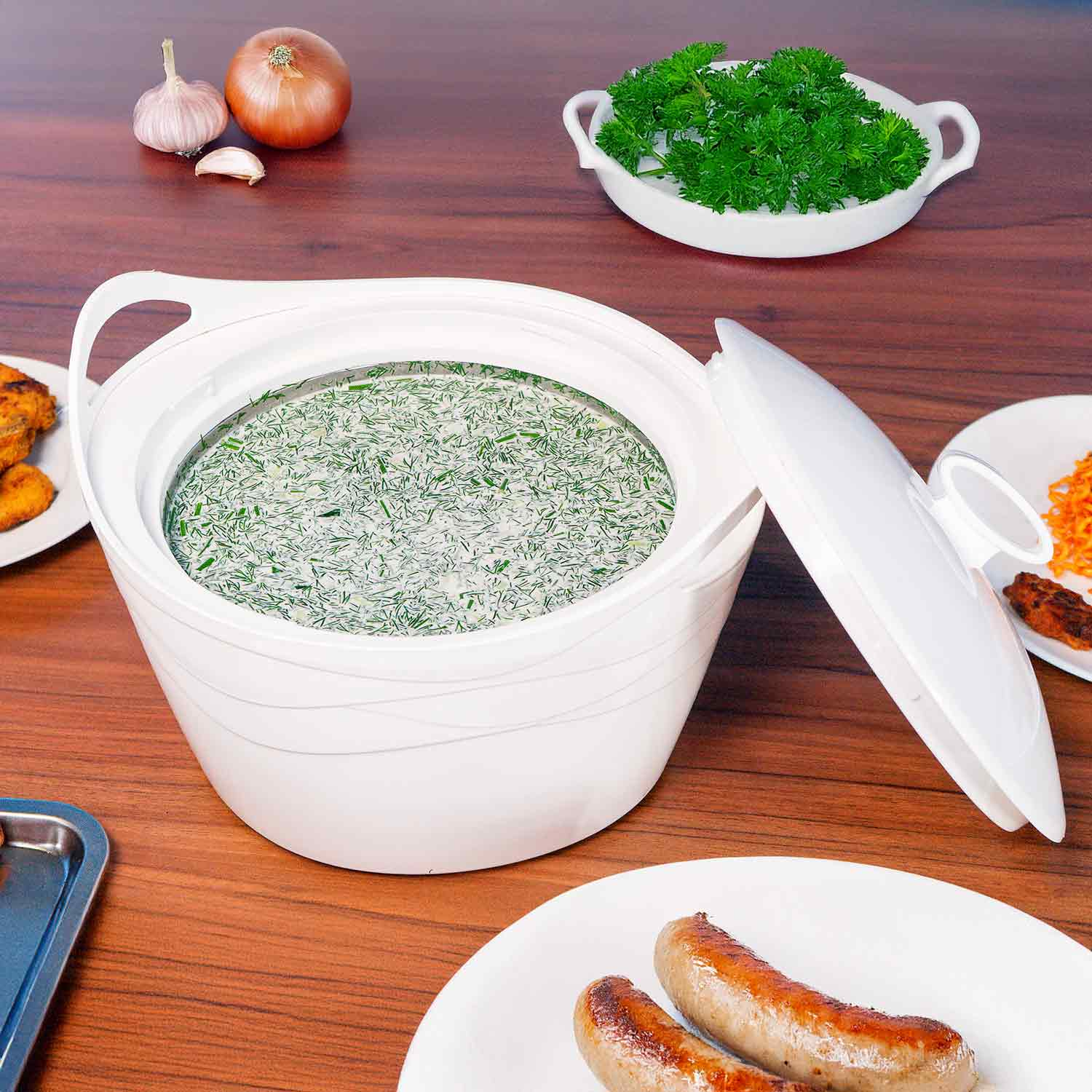 Weiße Schüssel mit Dill und Sauerrahm, umgeben von Speisen auf einem Holztisch.