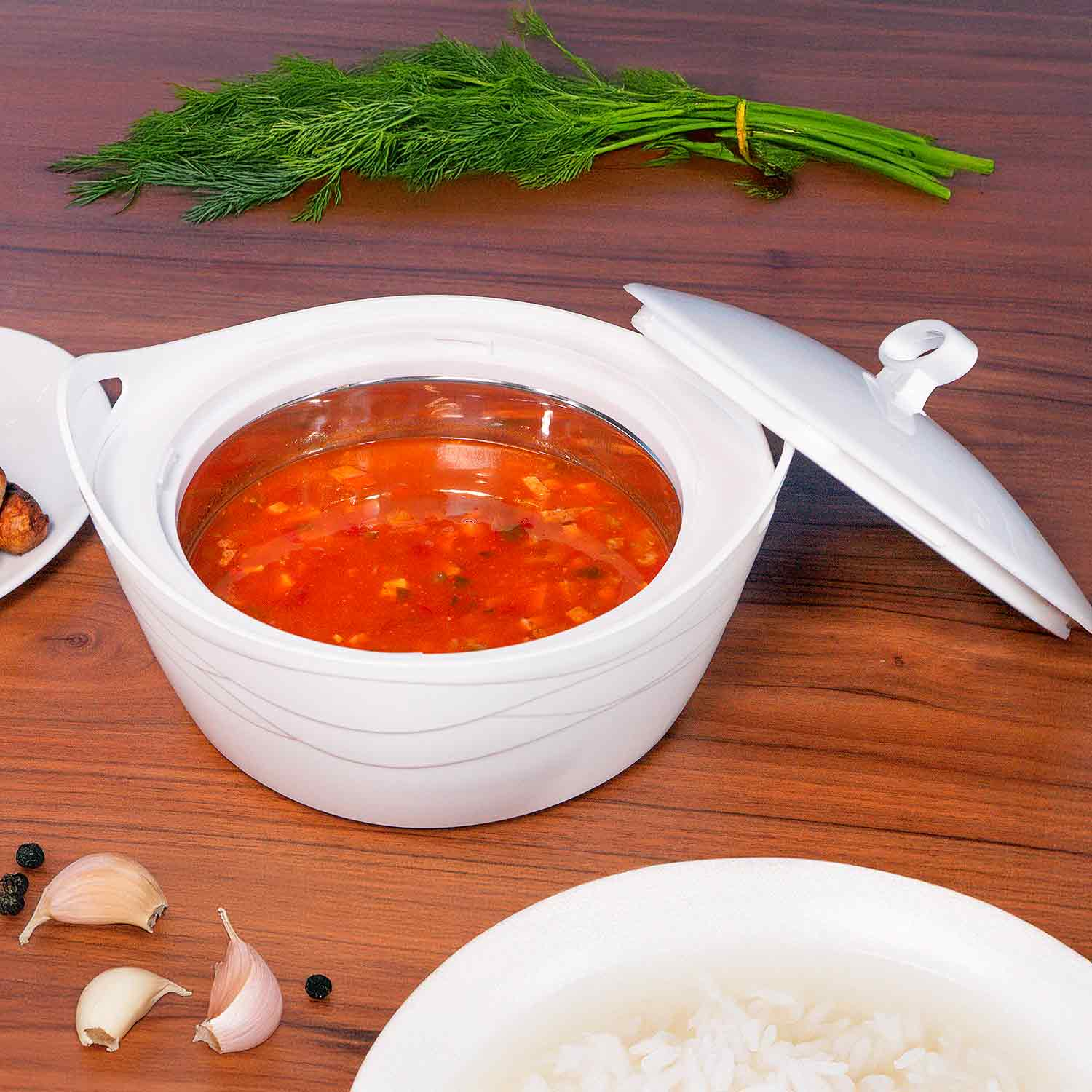 Weiße Servierschüssel mit roter Suppe, mit Dill garniert, auf Holztisch.