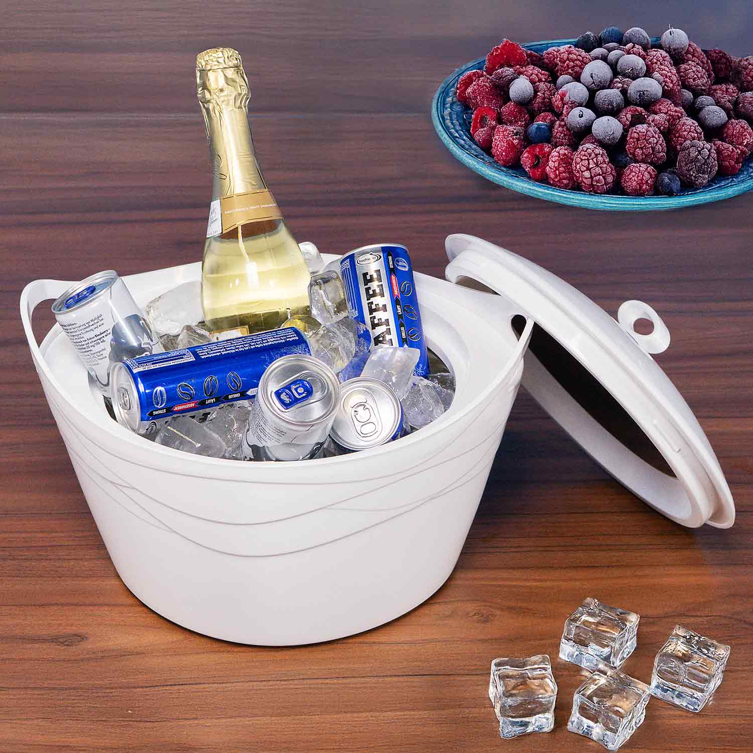 Eine weiße Kühlbox mit Eis, Getränken und einer Flasche Champagner, mit gefrorenen Beeren obenauf.