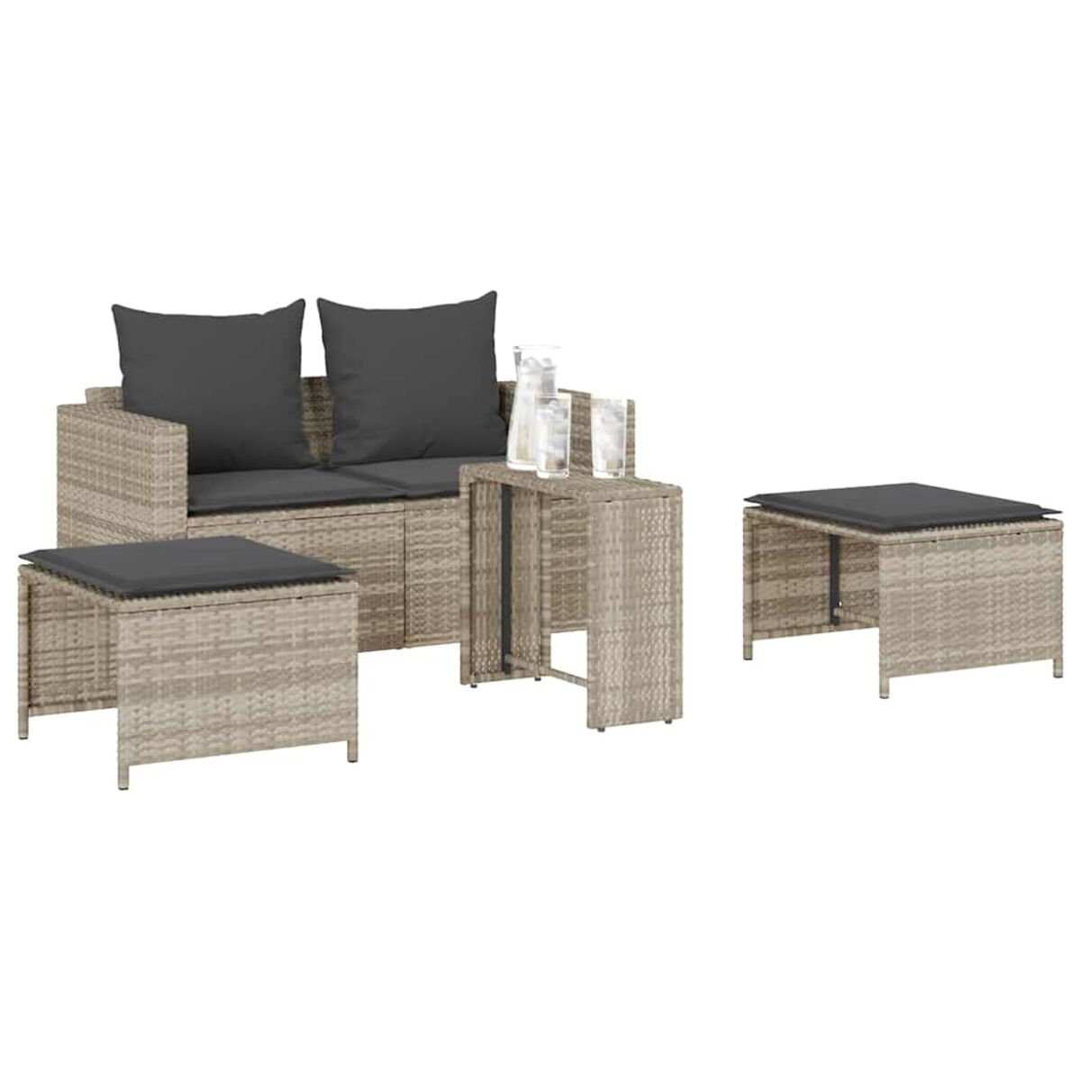 Set in rattan da esterno con due pouf, tavolino e divano con cuscini. Tonalità neutre, sfondo bianco.