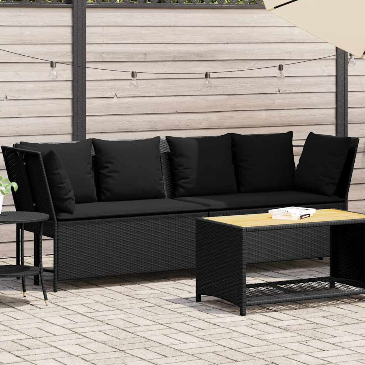 Set di mobili in rattan nero per esterni: divano, tavolino e tavolino. Sfondo verde.