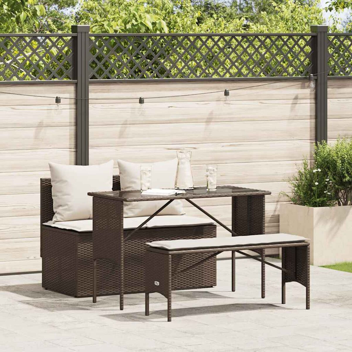 Ein braunes Ess-Set aus Korbgeflecht im Freien mit Tisch, Bank und zwei Stühlen auf einer Terrasse.