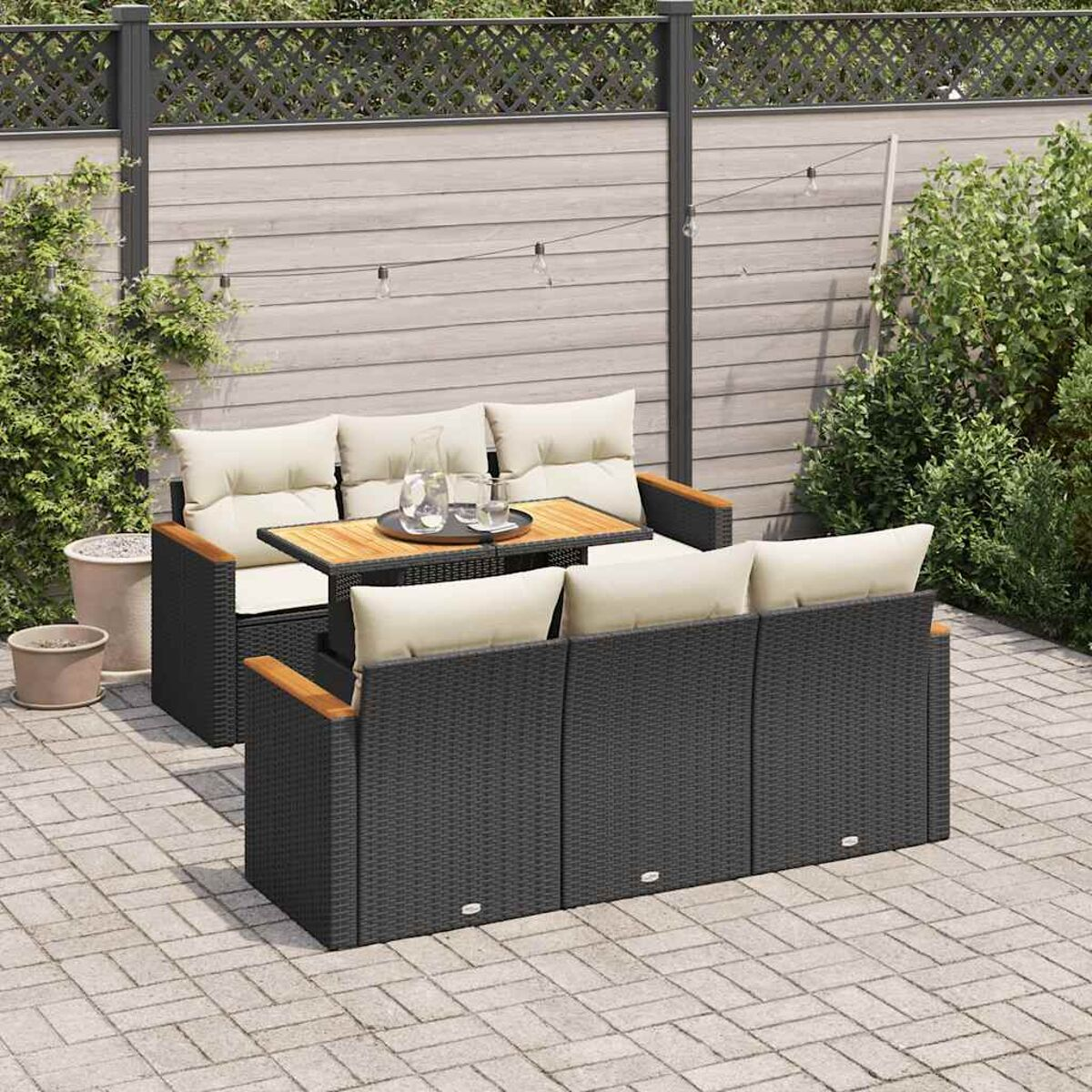 Set divano in rattan da esterno con tavolo, cuscini e bevanda.