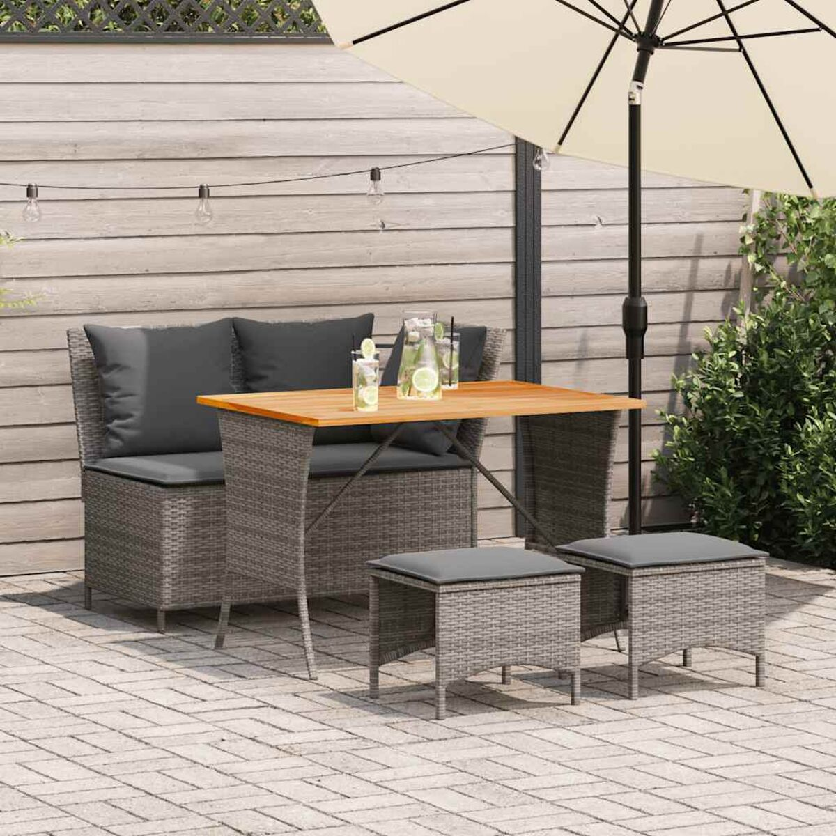 Set di sedute per esterni con cuscini grigi, un tavolo in legno e un ombrellone su un patio.