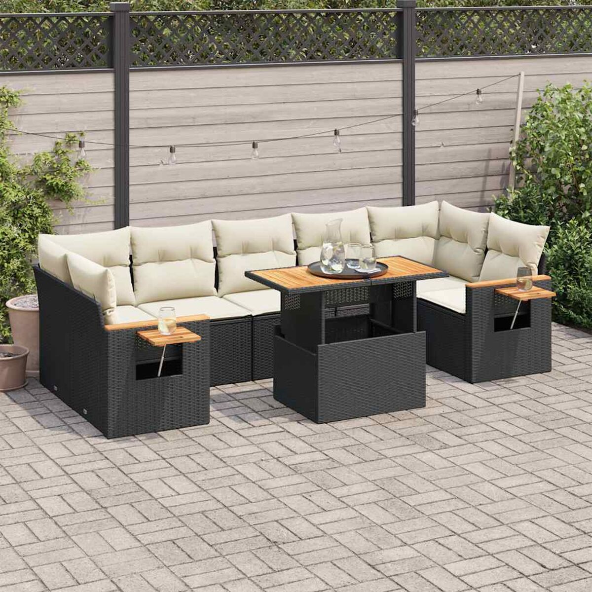 Divano componibile da esterno con tavolo e cuscini. Include tavolini in legno, un patio e una recinzione sullo sfondo.