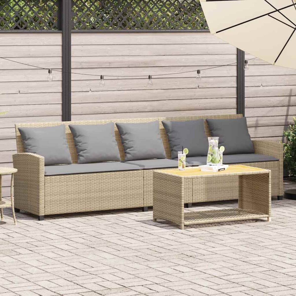 Un set da patio con divano, tavolino e cuscini, con uno sfondo di recinzione.