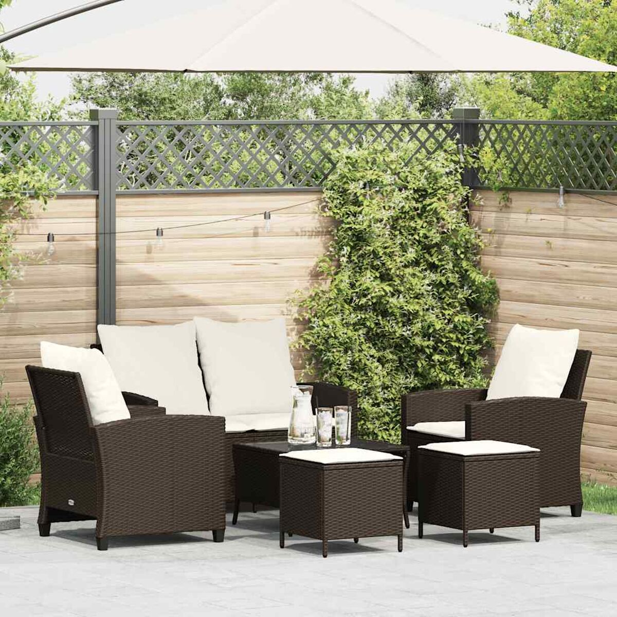 Set da patio all'aperto: sedie in vimini marroni, divano, tavolo e ombrellone in un giardino.