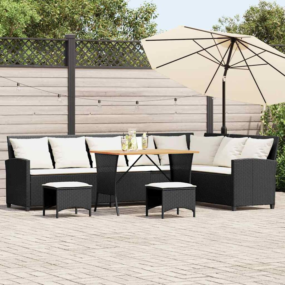 Set di sedute da esterno. Due divani, un tavolo e due pouf. Su un patio pavimentato.