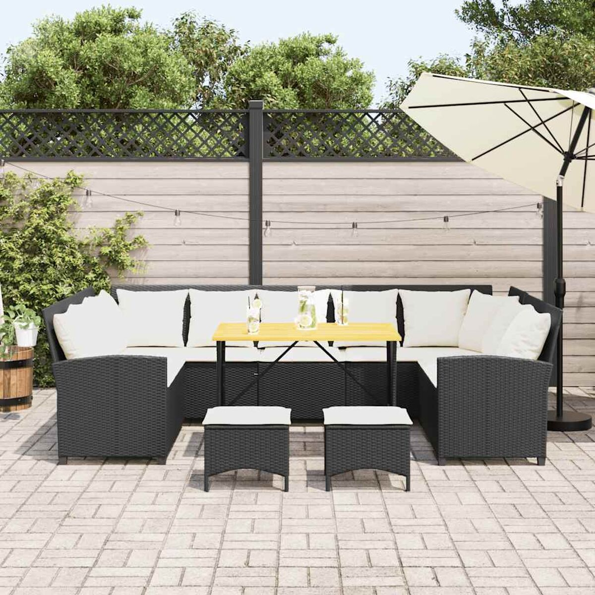 Schwarzes Terrassenmöbel-Set mit weißen Kissen. Tisch mit Getränken, Sonnenschirm.