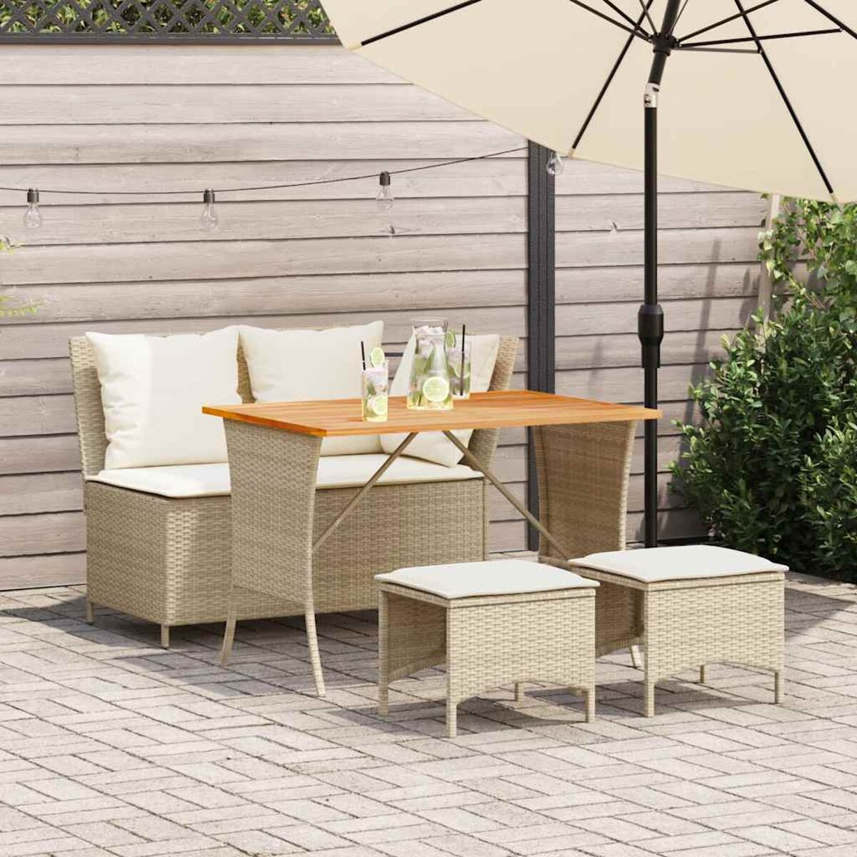 Outdoor-Rattanmöbelset: Sofa, Tisch und Hocker. Mit cremefarbenen Kissen und Sonnenschirm.