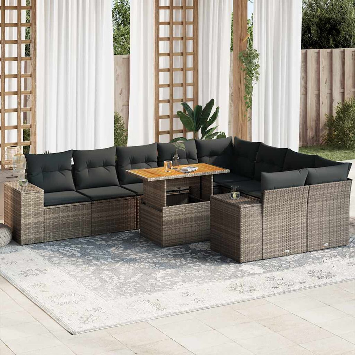 Set patio esterno con cuscini grigi. Include divano, tavolo e sedie. Scena soleggiata.