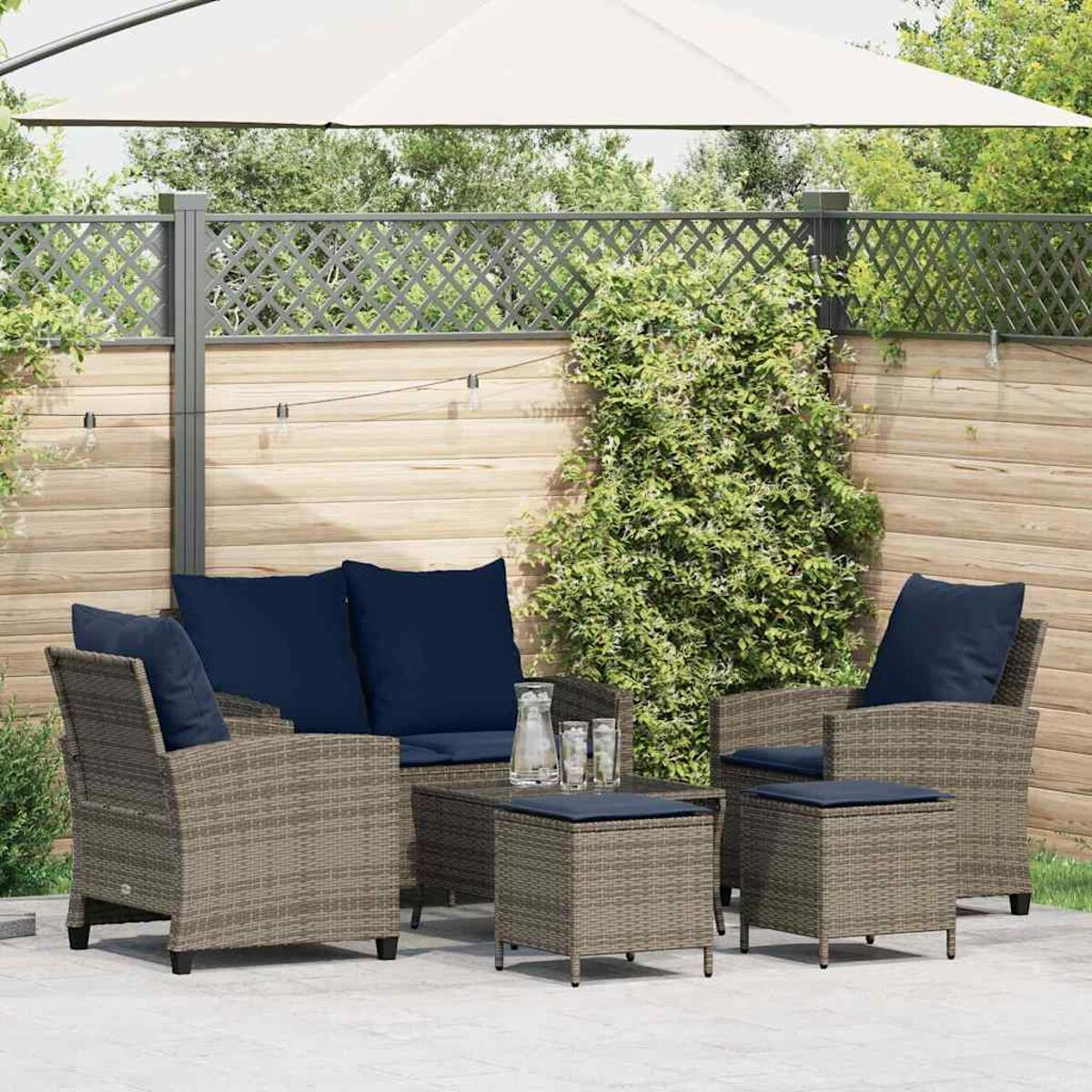 Set da patio all'aperto con divano, due sedie e un tavolo. Cuscini blu e ombrellone bianco sullo sfondo.