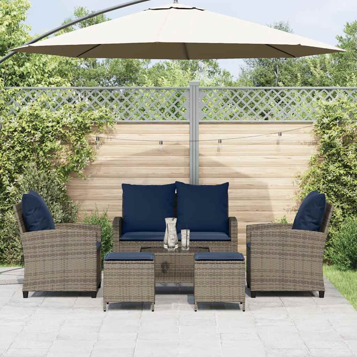 Set da patio all'aperto con divano, sedie e pouf. Include ombrellone, tavolo e piante sullo sfondo.