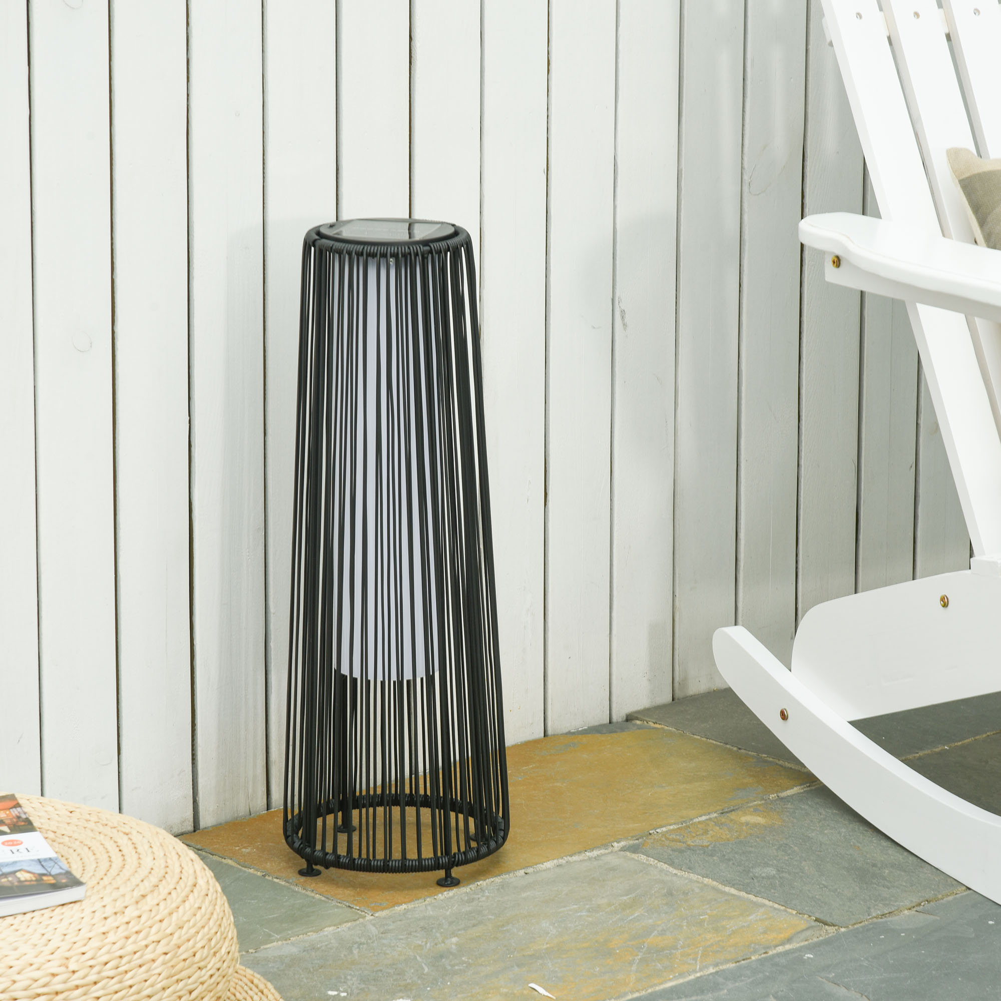 Schwarze Metall-Außenlampe mit weißem Licht, stehend auf einer Stein-Terrasse.