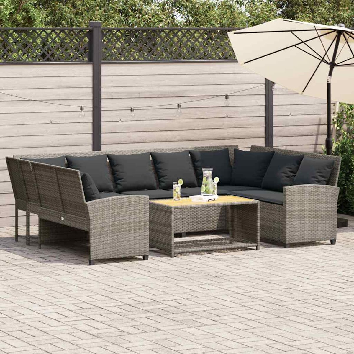 Ein Terrassenset mit grauem Ecksofa, Couchtisch und Getränken.