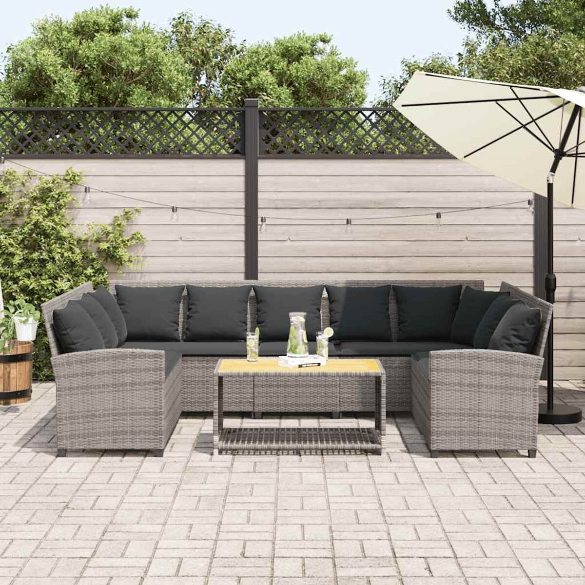 Graues Korbsessel-Outdoor-Sofa mit schwarzen Kissen, Tisch und Schirm.